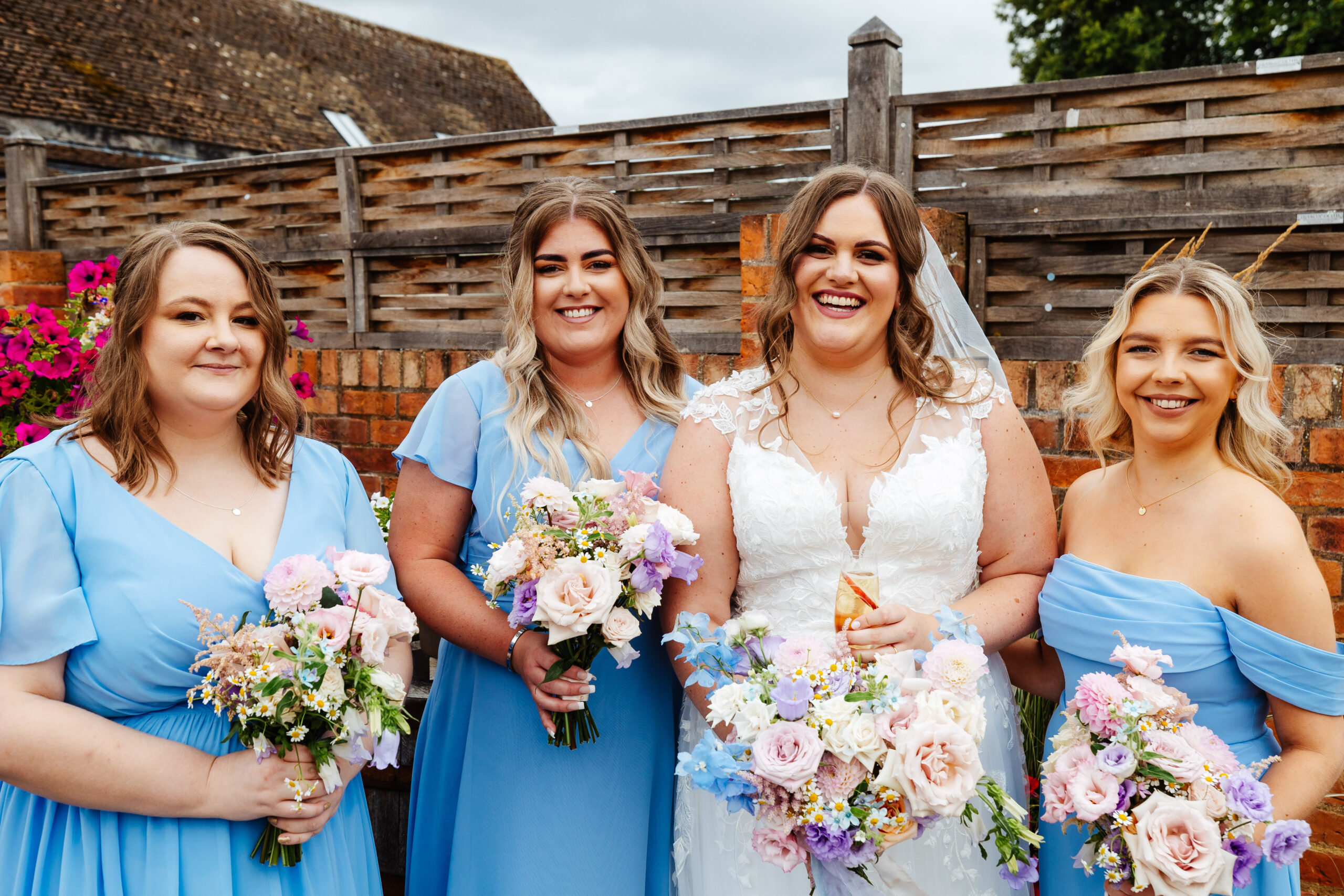 The bride and her bridesmaids outside. They are looking at the camera and smiling.