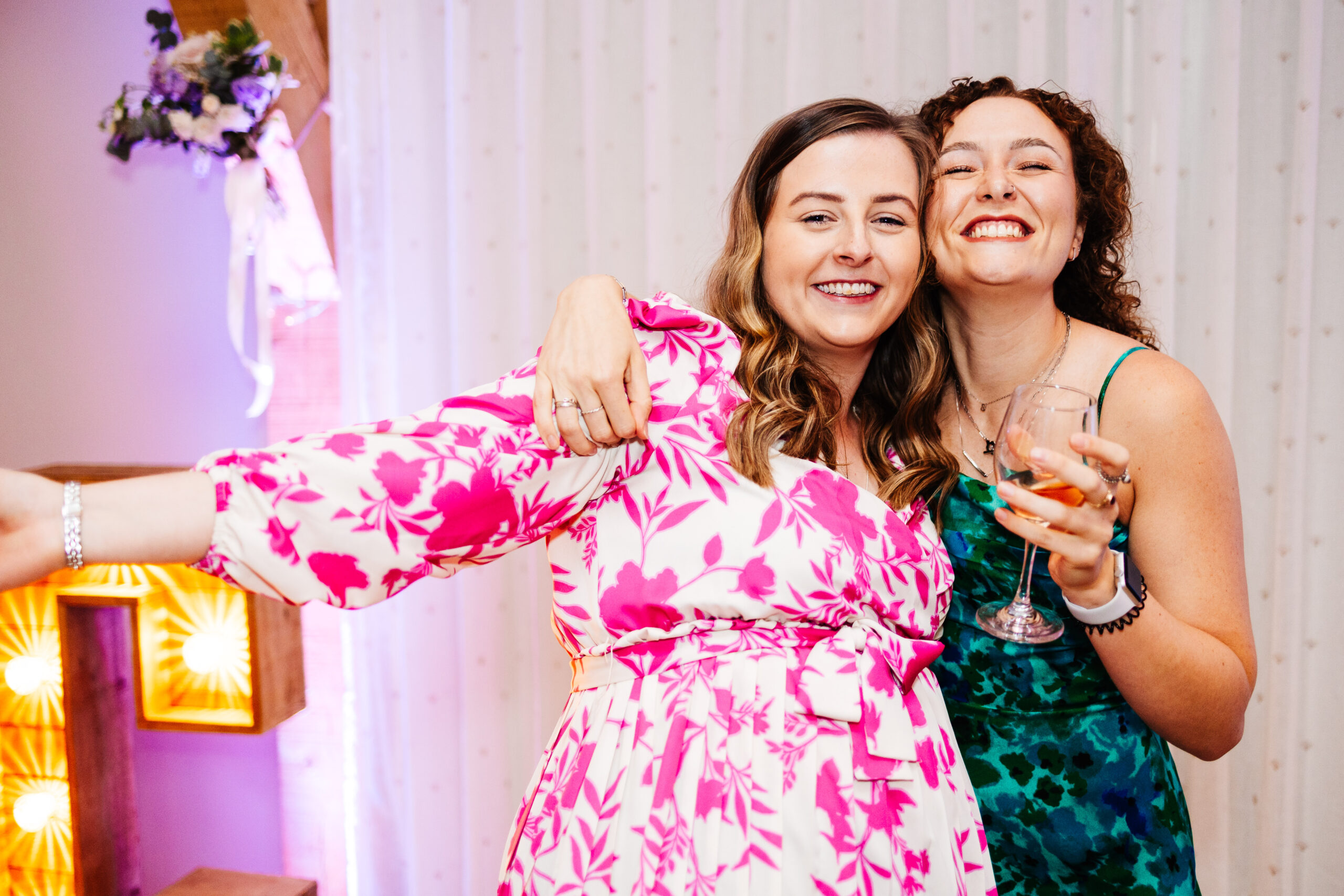 Two guests on the dancefloor having fun. One has a drink in her hand and the other has her arm out to the side as if they are dancing.