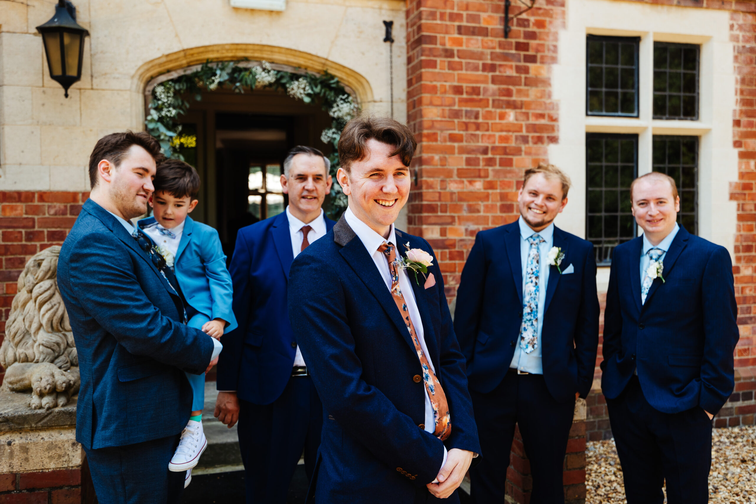 The groom and his groomsmen. They are looking at the groom and smiling.