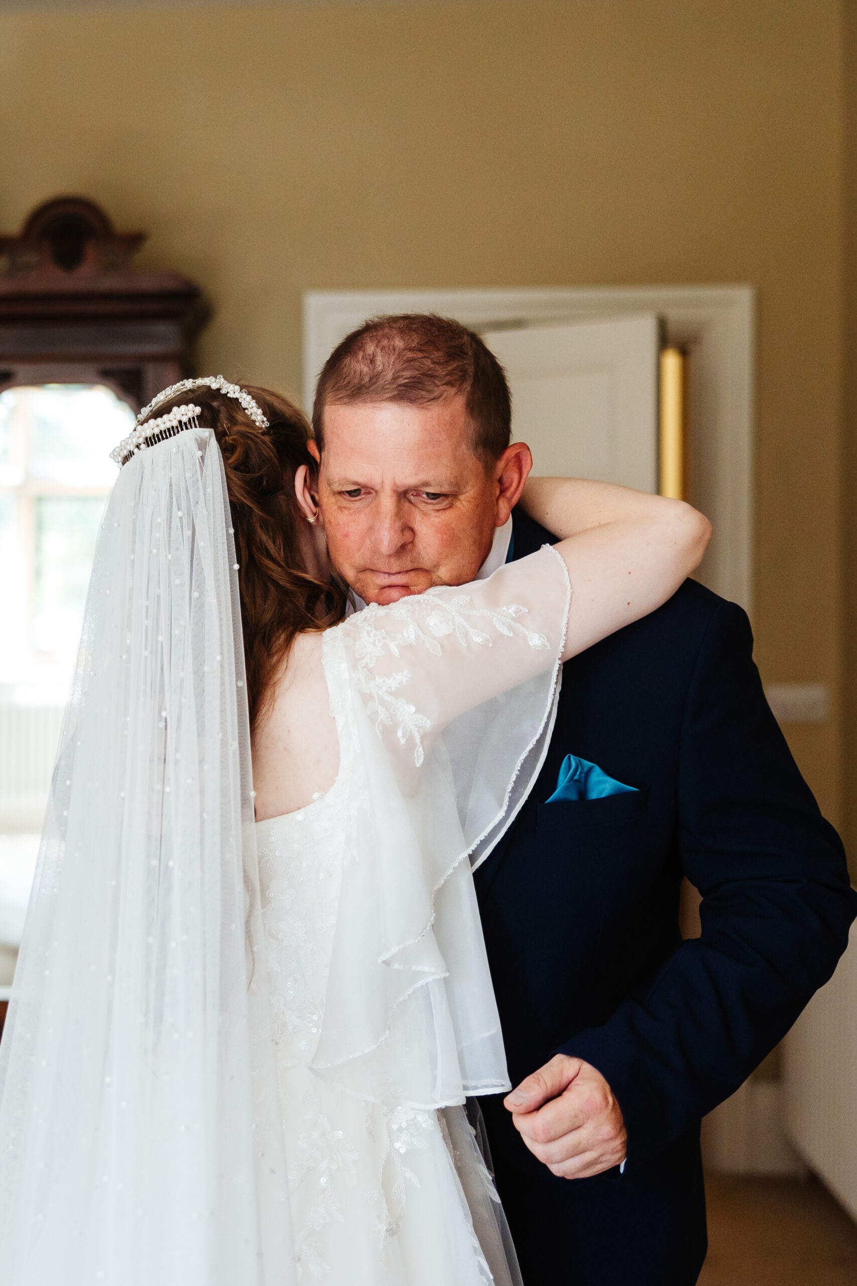 The bride and father of the bride sharing an intimate moment, hugging. You can see the Father's face and he looks proud, happy and emotional.