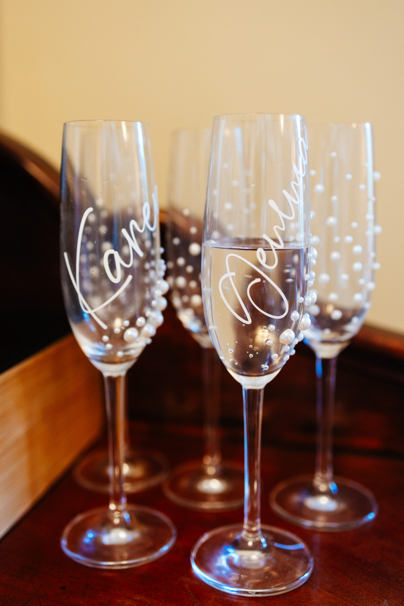 Champagne glasses that are personalised with the bridesmaids names on. They also have pearls on the side of them. The names are written in a calligraphy style font.