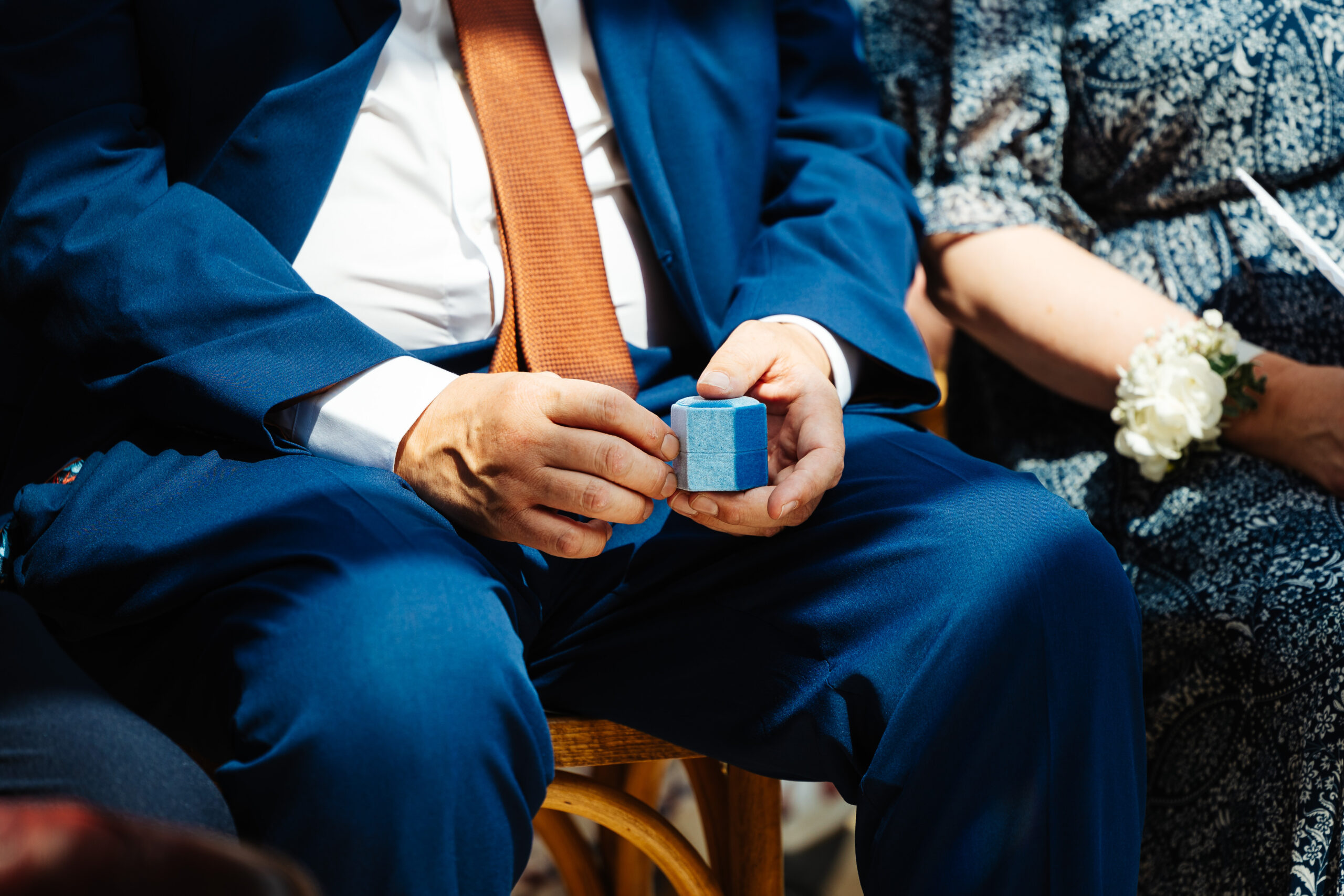 One of the groomsmen holding the ring box. The ring box is a hexagonal box in pale blue velour.