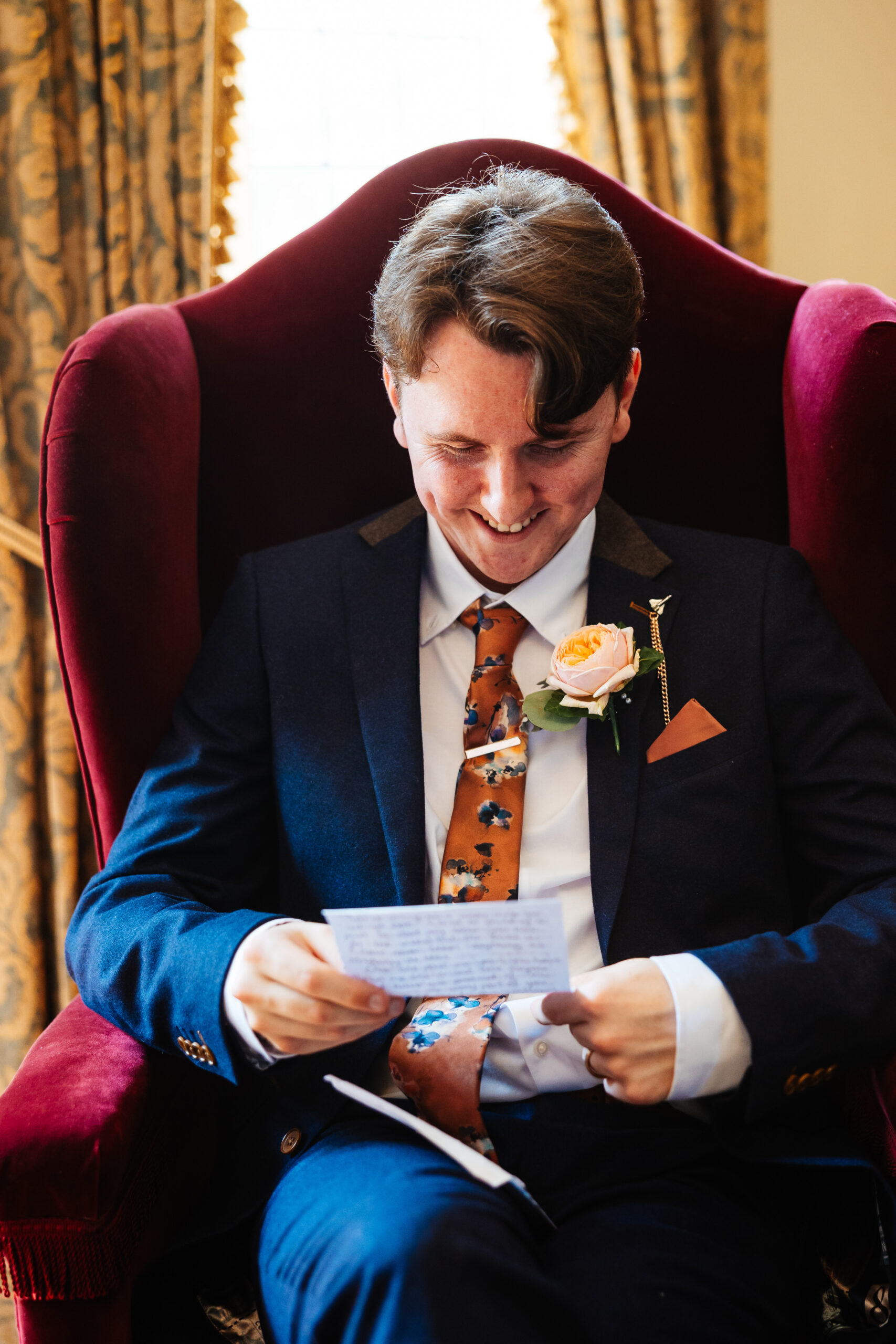 The groom sat down on a chair reading a note from his bride. 