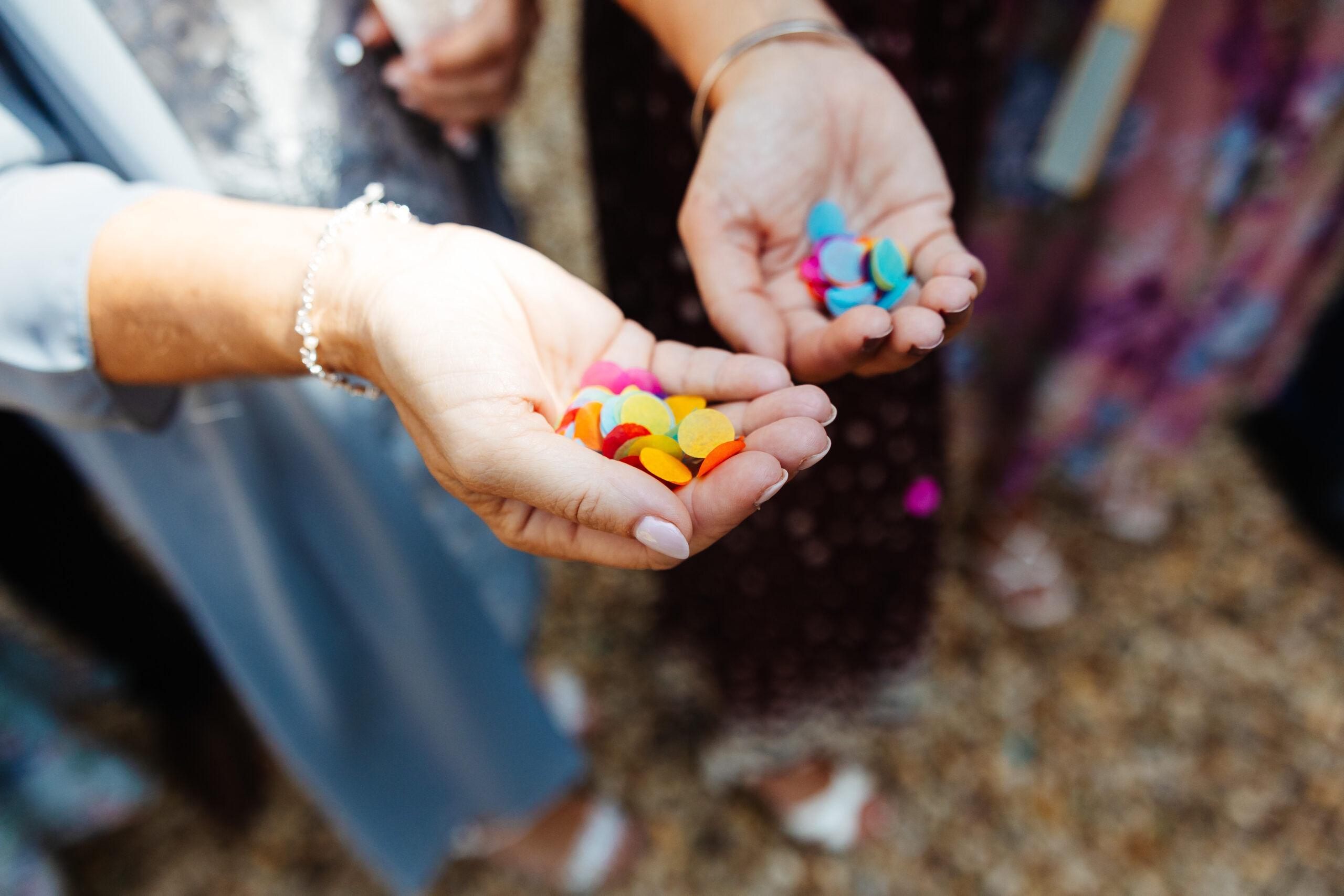 A guests hands - they are holding little bits of coloured confetti.