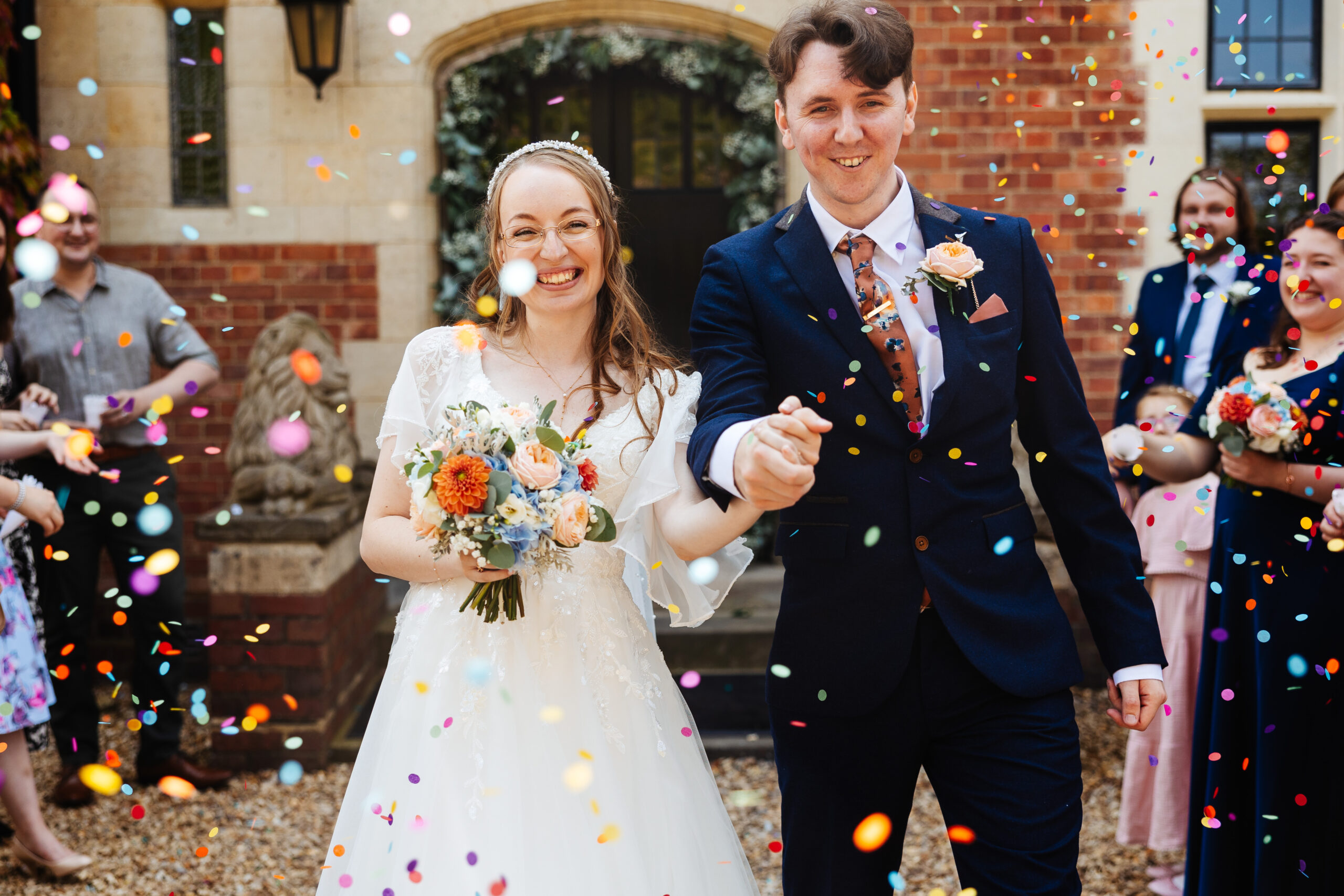 The bride and groom outside. The guests are throwing confetti at them.