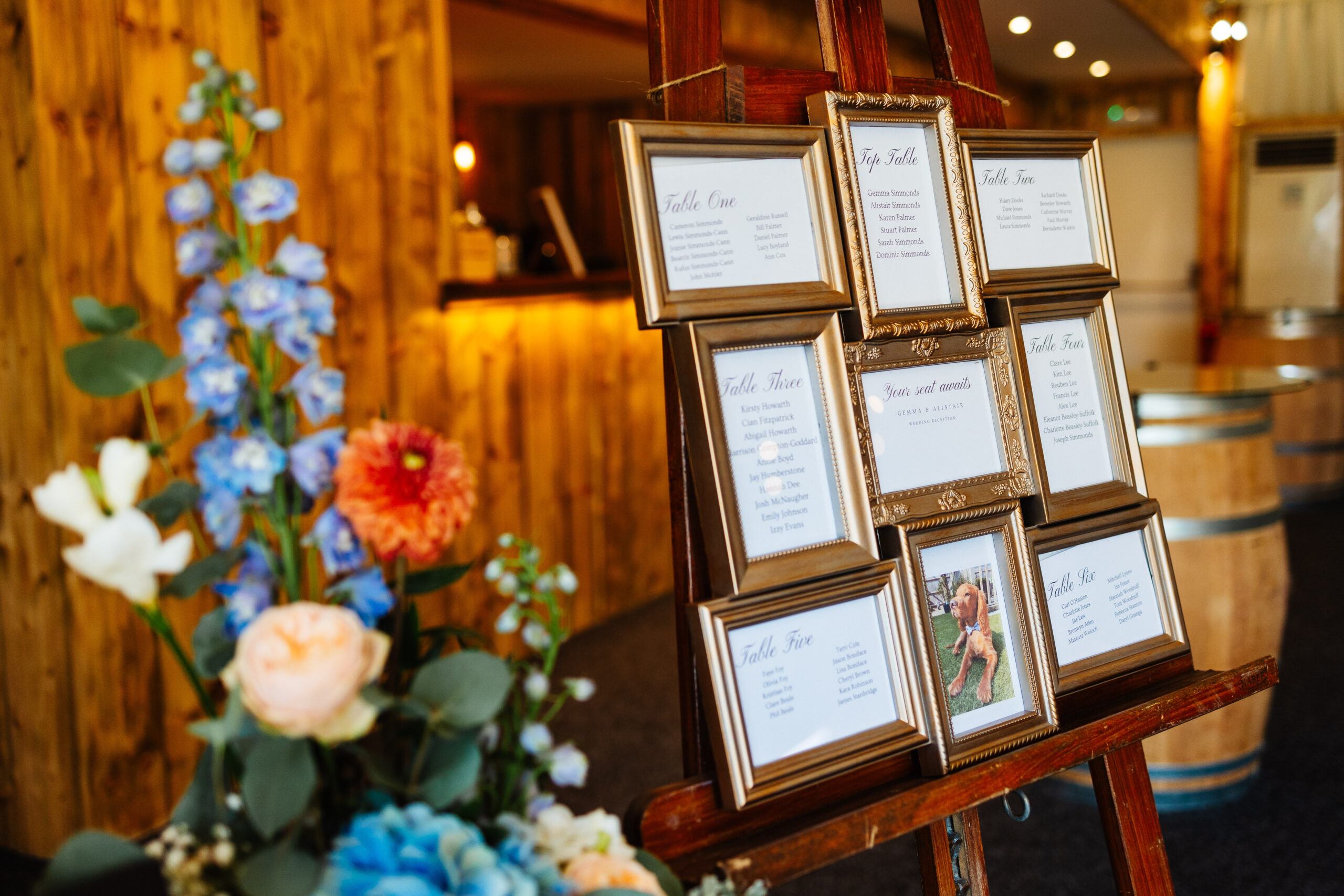 The table plan for the day. The table plans are gold frames and it is on an easel.