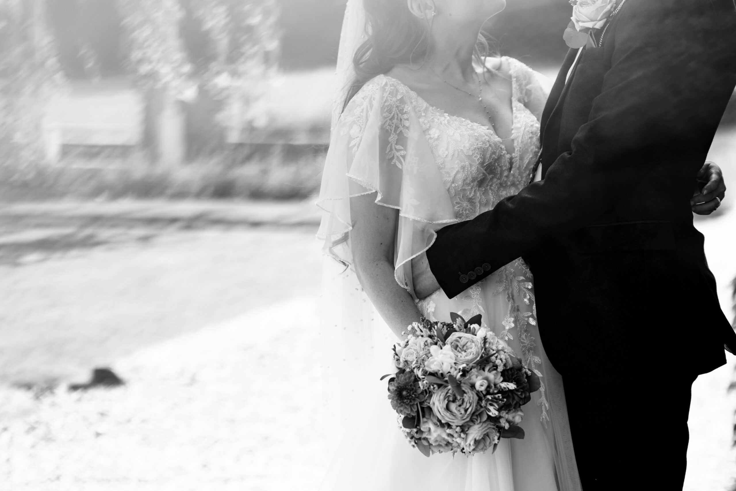 A black and white image of the bride and groom bodies. They are holding each other. 