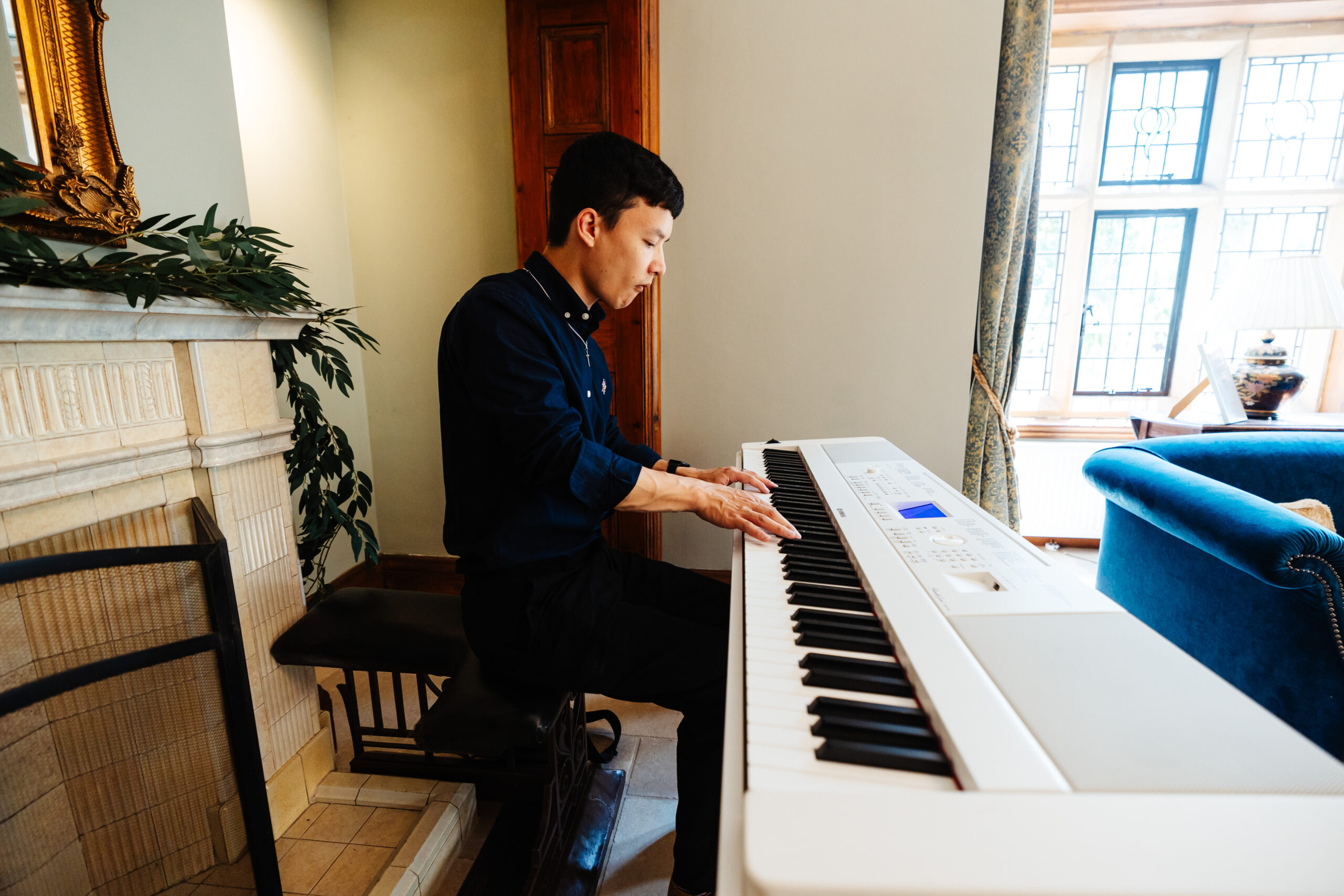 A man playing piano. He is in a navy shirt.