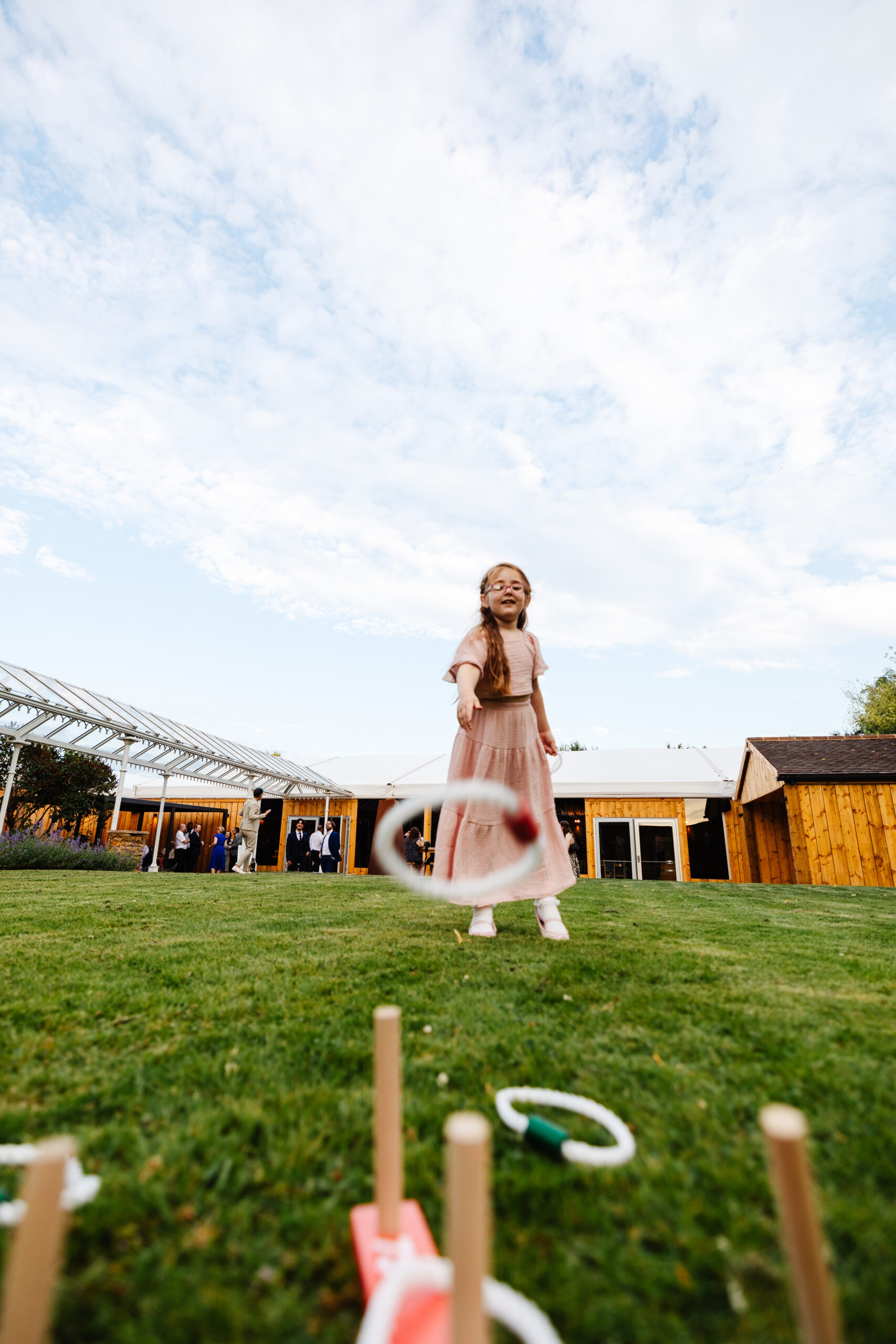 A little girl playing hoopla in the garden.