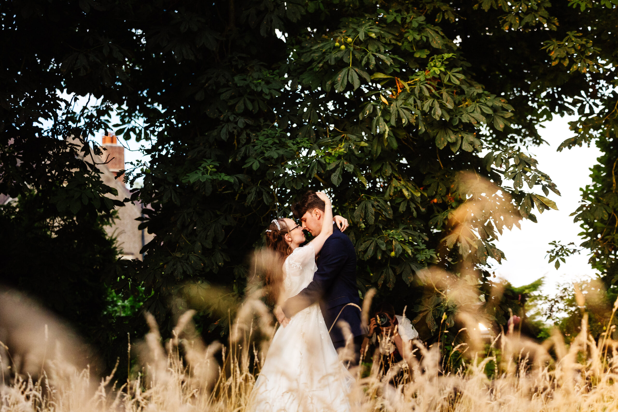 The bride and groom in a cornfield. They are holding each other and looking at each other.