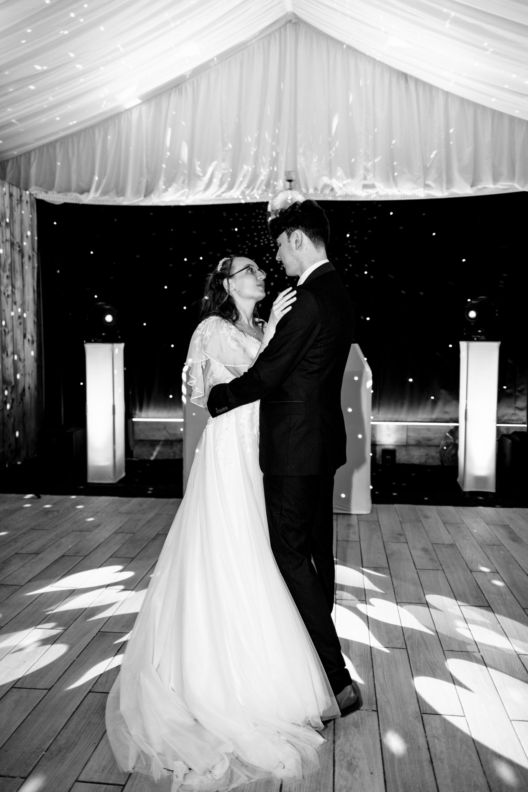 A black and white image of the bride and groom's first dance. They are embracing each other, looking at each other.