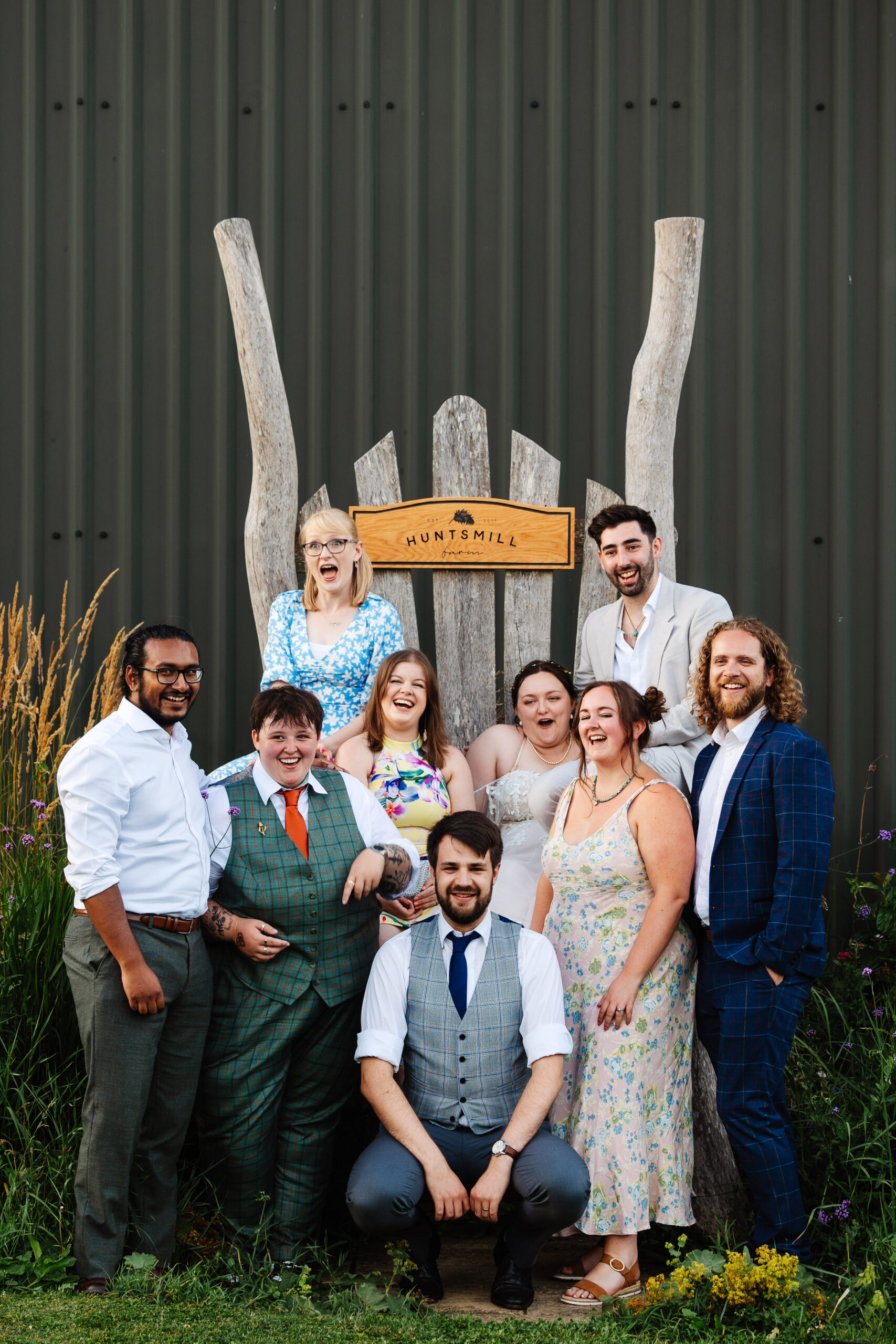 A group of the brides' friends. They are sat on a large wooden thrown which has the venue's branding on top on a wooden post.