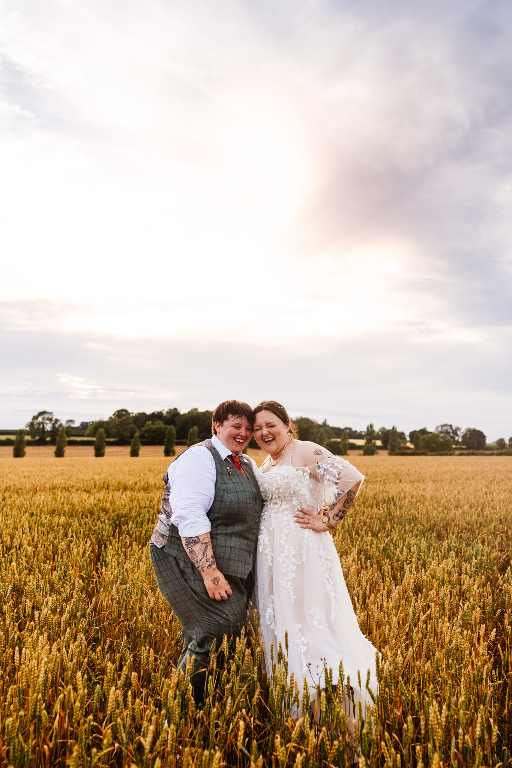 The brides in a corn field. They are laughing, happy and smiling.