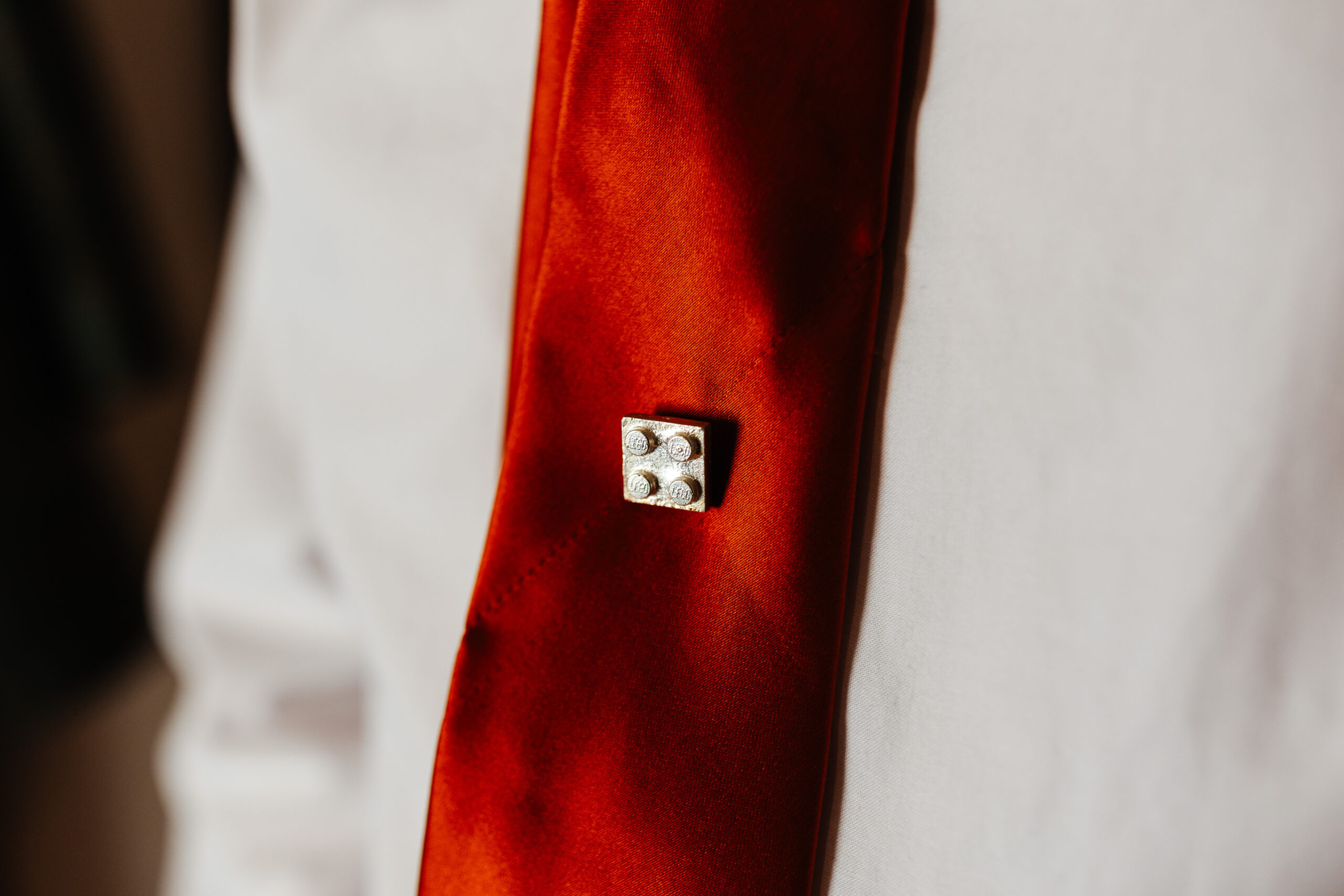 A little lego piece on a burnt orange tie.