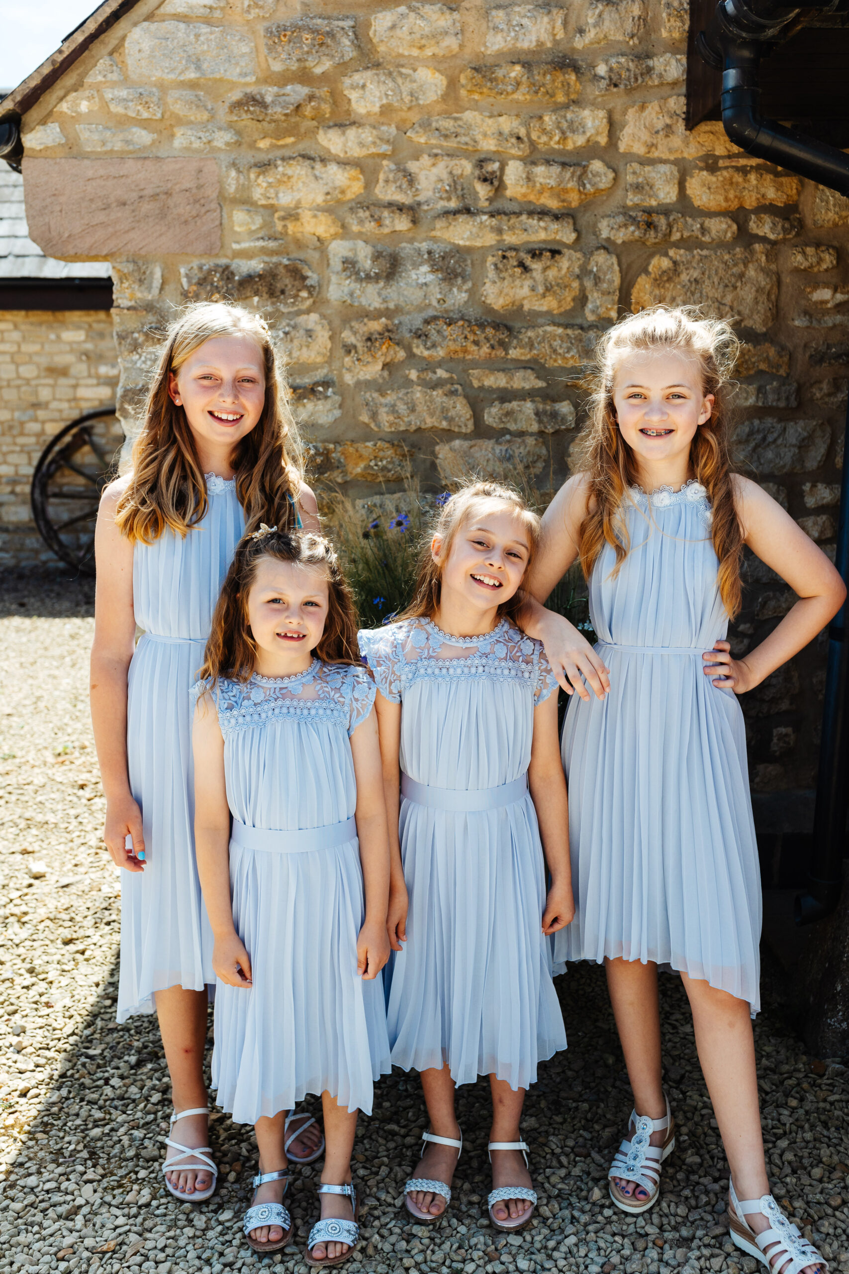 A photo of four of the bridesmaids. They are wearing pale blue dresses and have their hair curled. They are all smiling at the camera