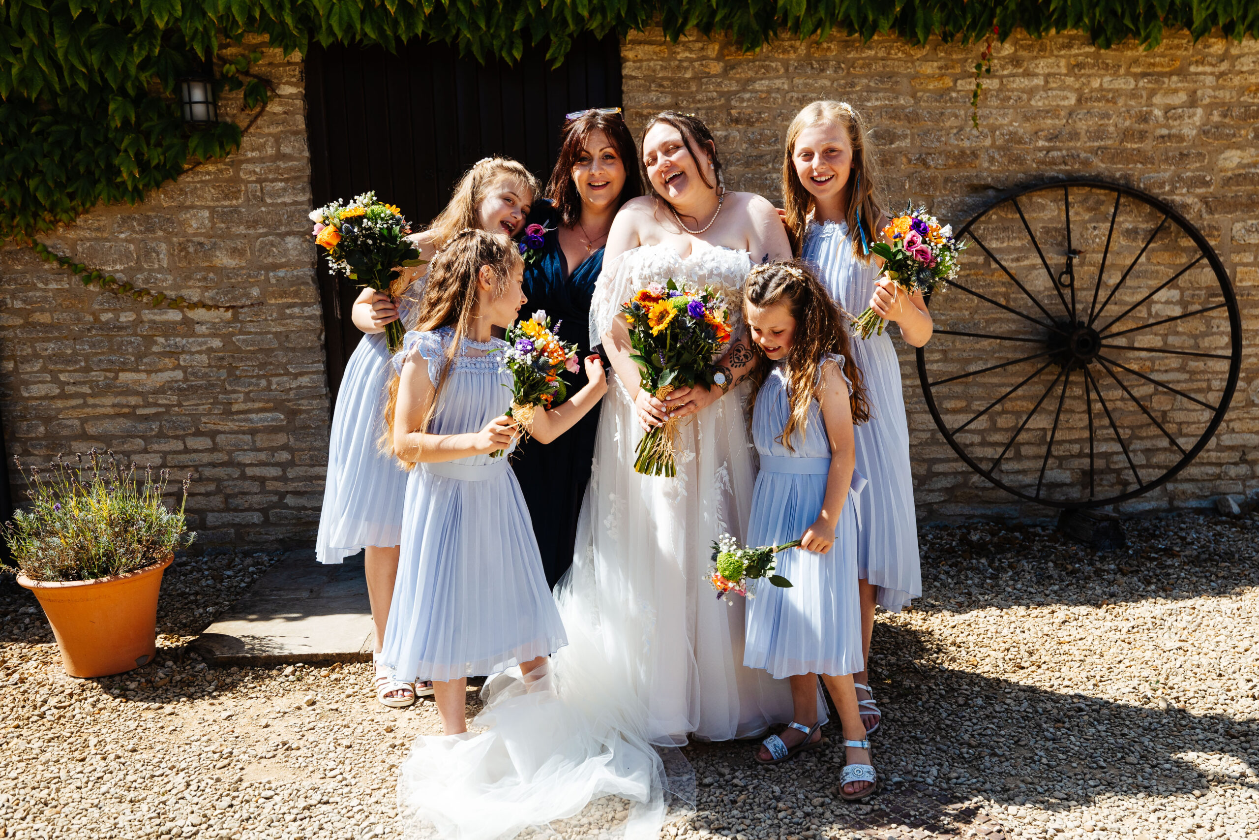 A photo of one of the bride's and her flower girls. They are all holding a bouquet of brightly coloured flowers. They are all happy and you can feel their great energy.