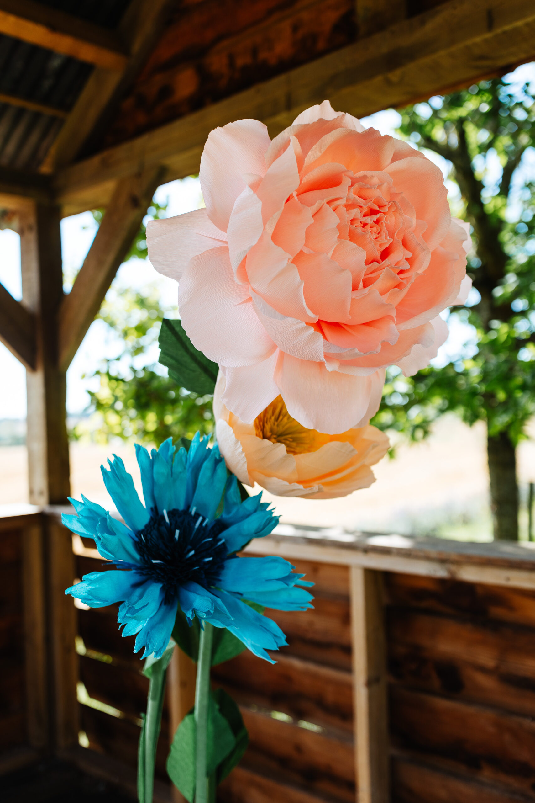 Beautiful, bright paper flowers. They are blue, orange and pale yellow.