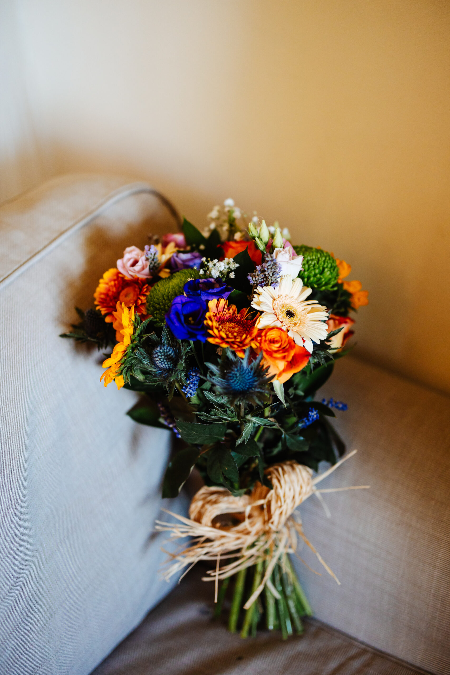 A large bunch of very brightly coloured flowers. They are tied up with rope at the stems.