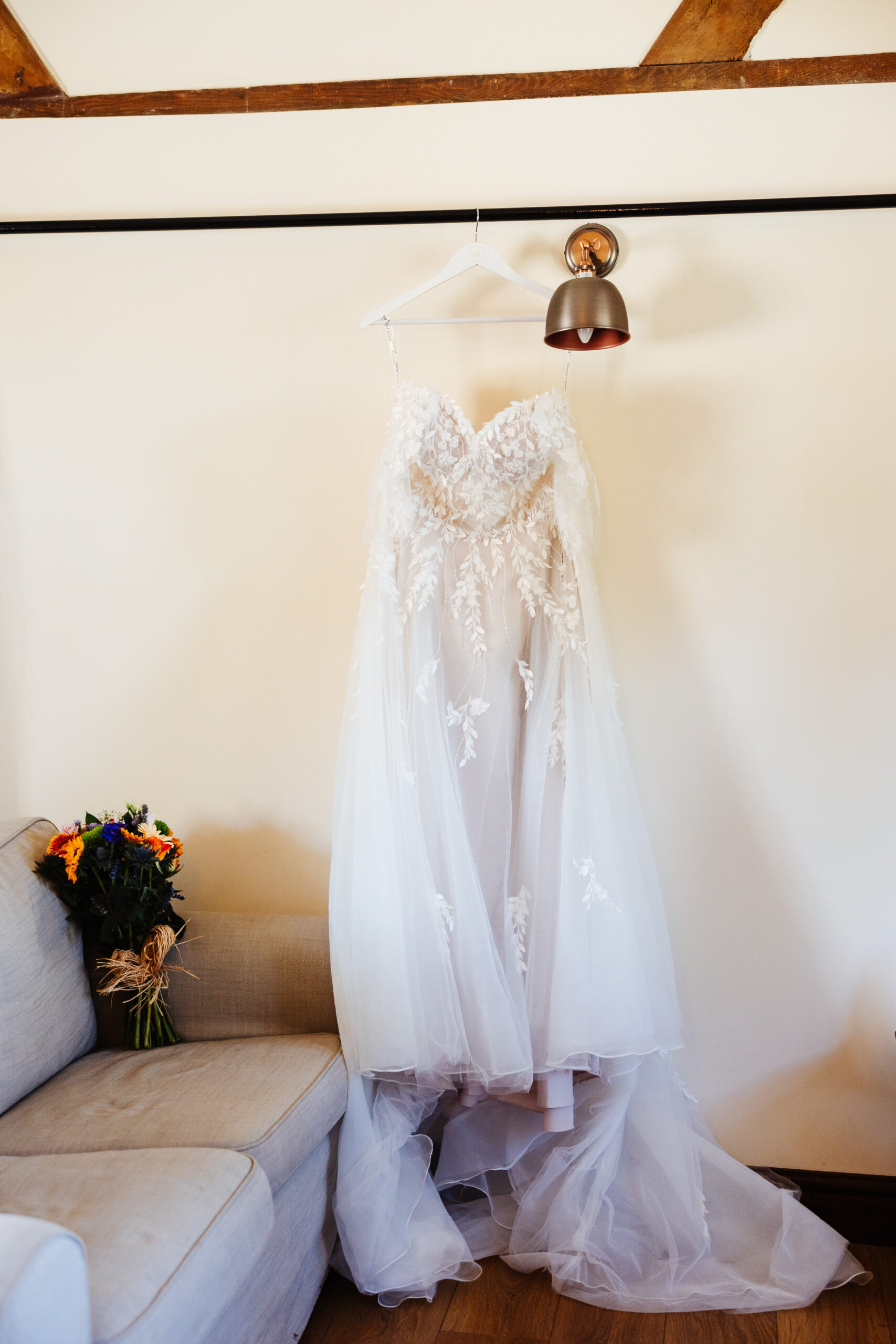 The bride's dress. It is strapless with beaded and lace detail on the front. There is a long train.