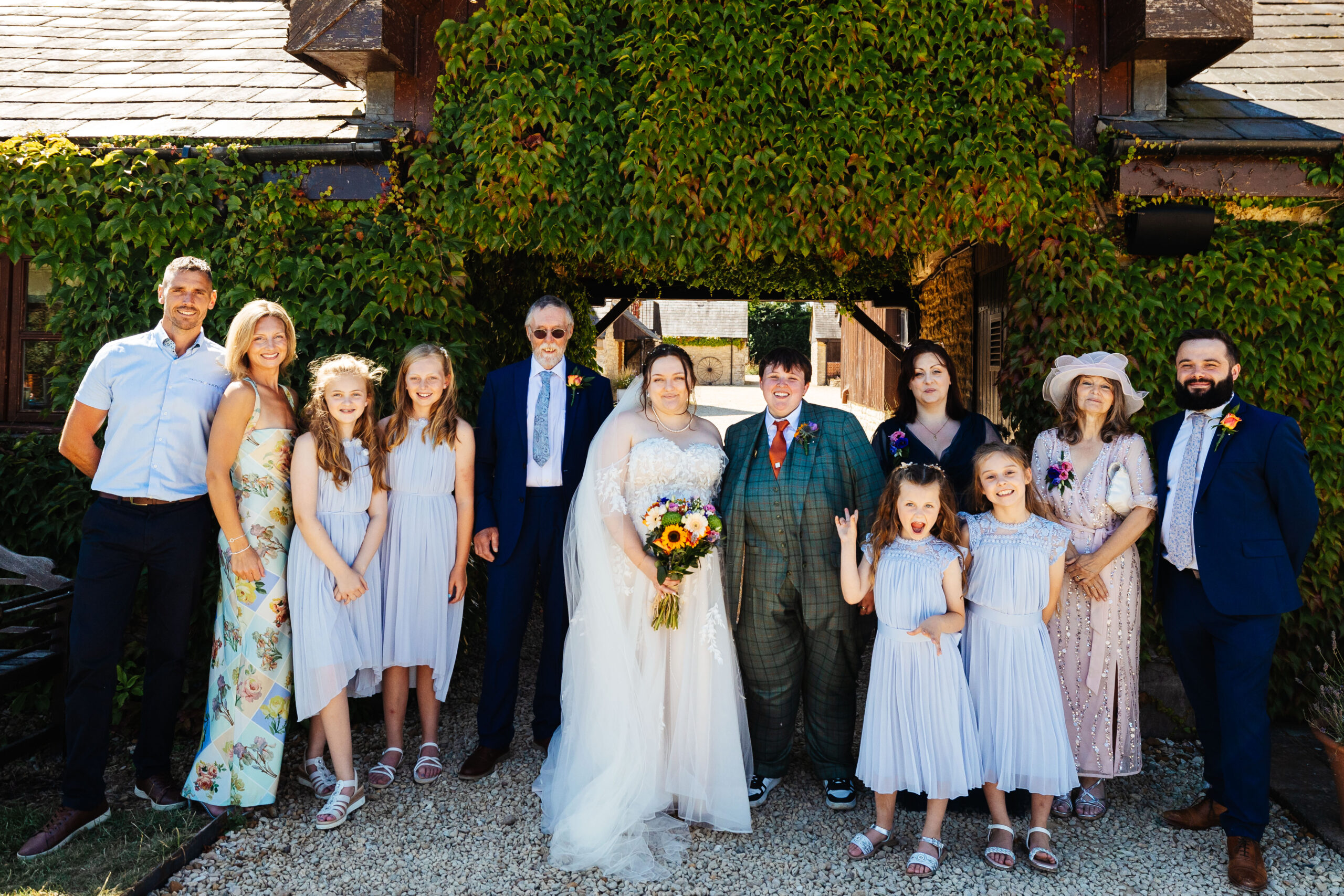 A group photo of the brides and their family. They are all smiling and looking at the camera.