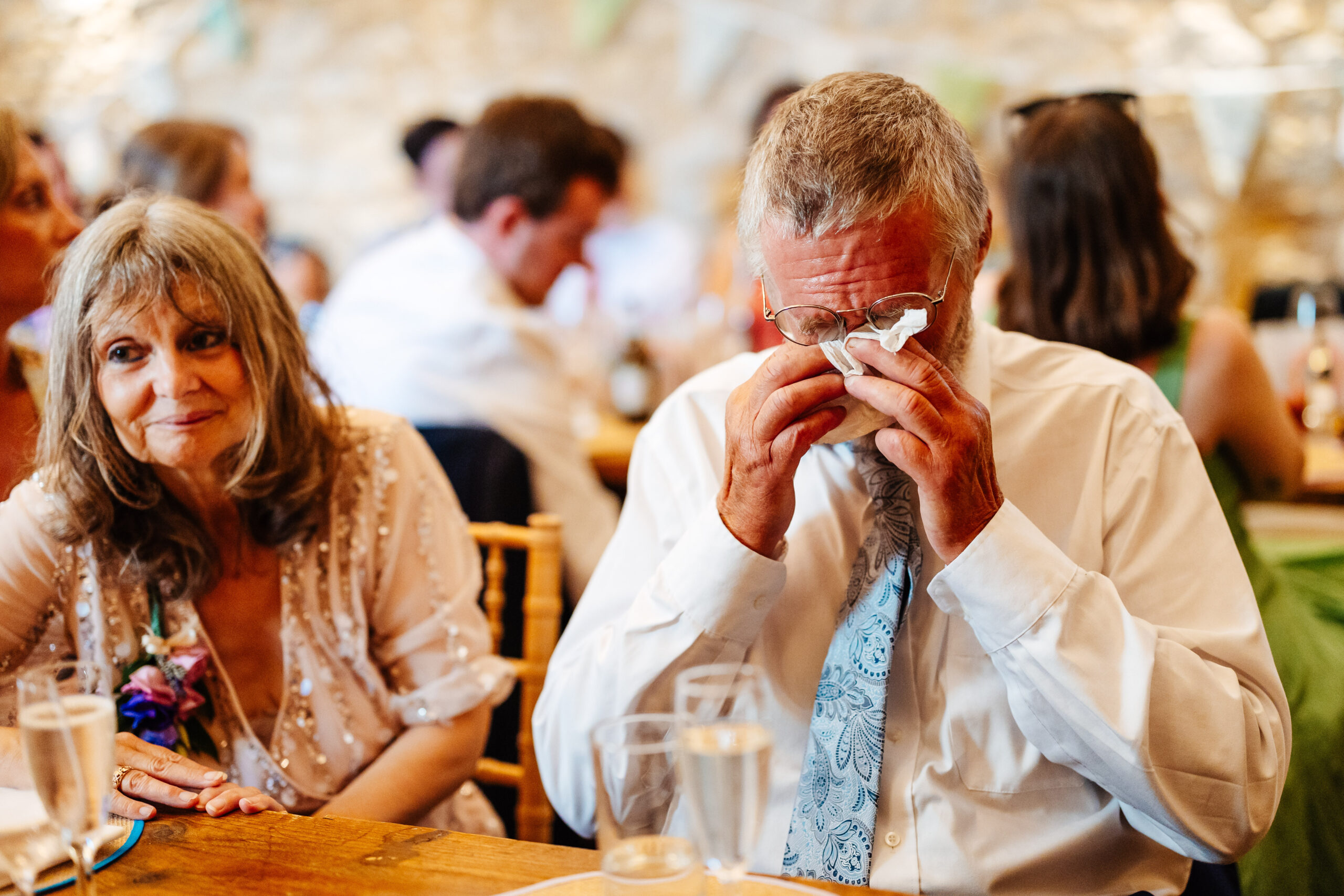 The father of the bride who is wiping tears away from his eyes as he has been crying during the speeches.