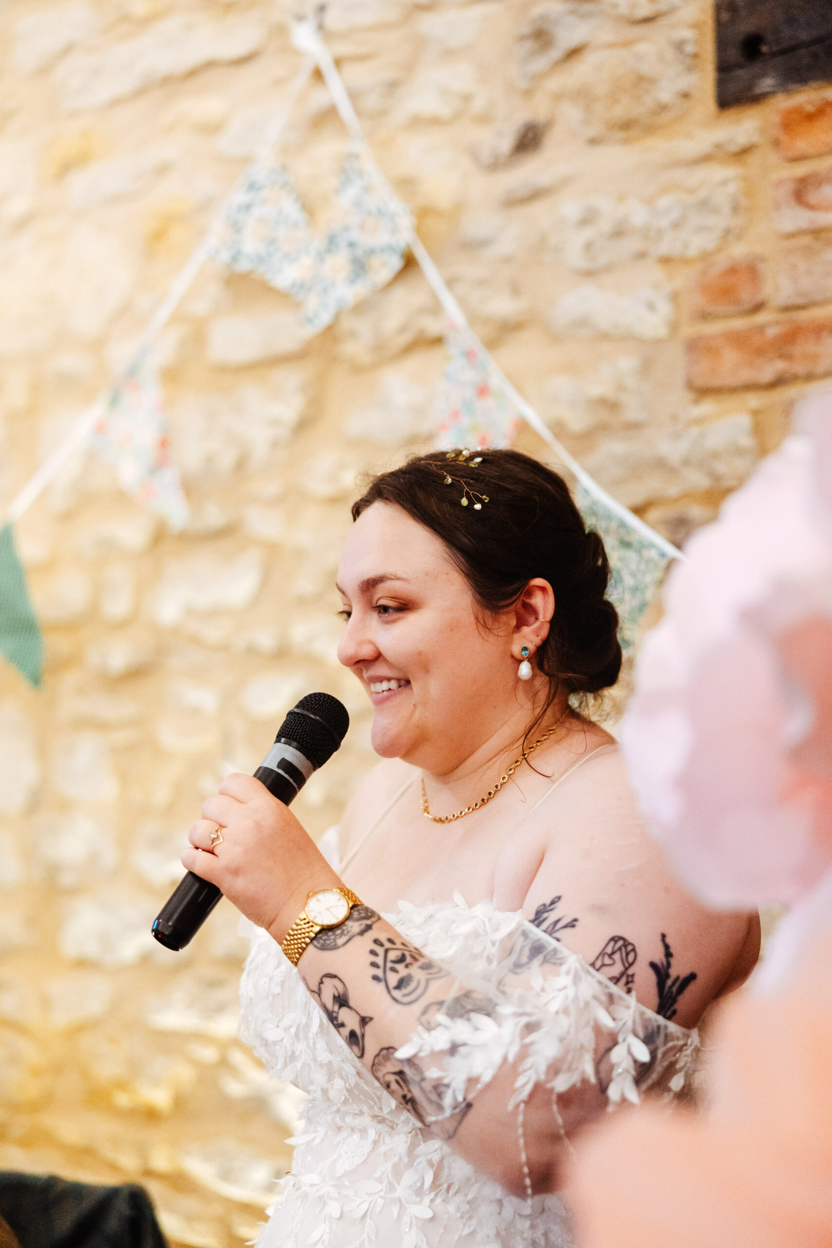 The bride and a microphone. She is doing a speech and has a big smile on her face.