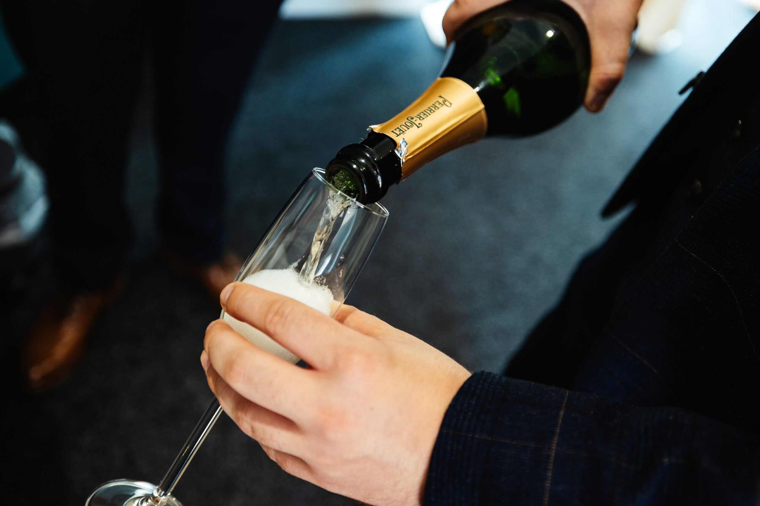 A tipped bottle of champagne, it is being poured in to a glass.