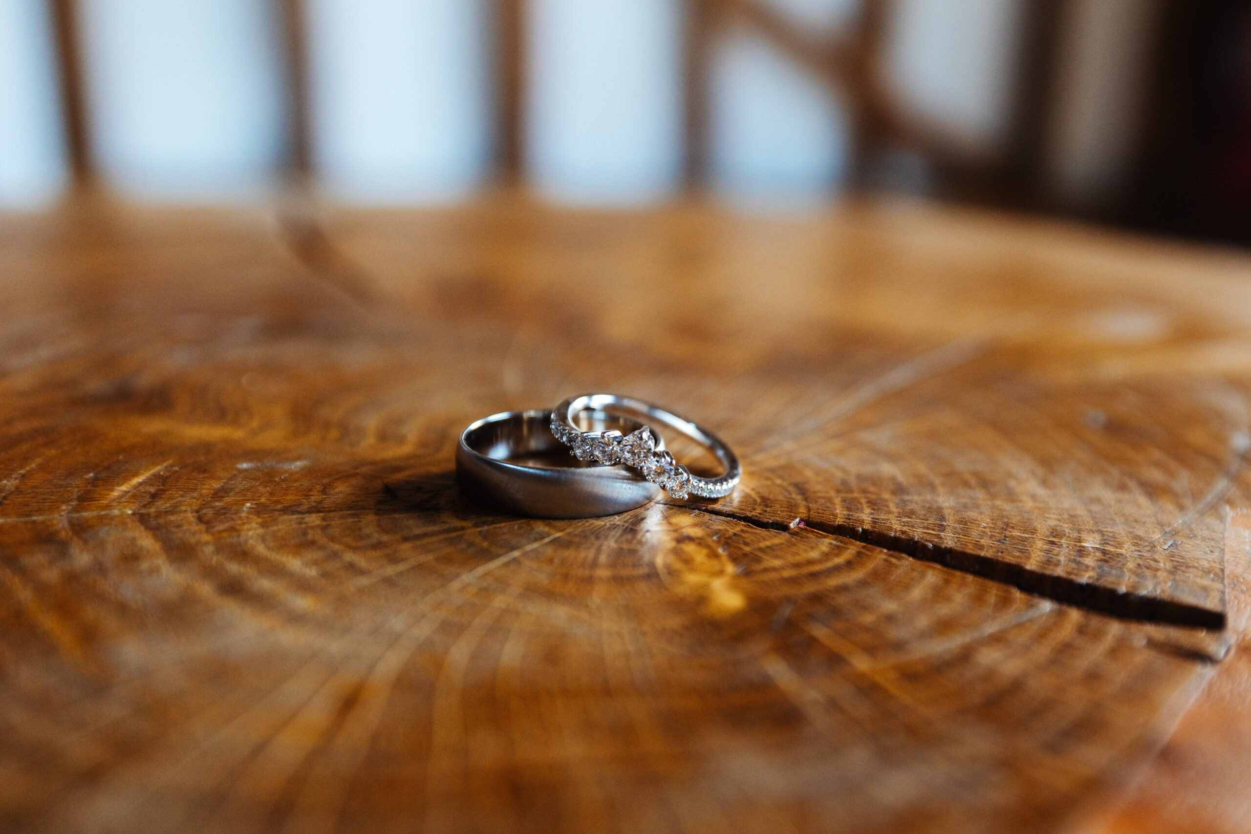 Two silver wedding rings on an oak table.