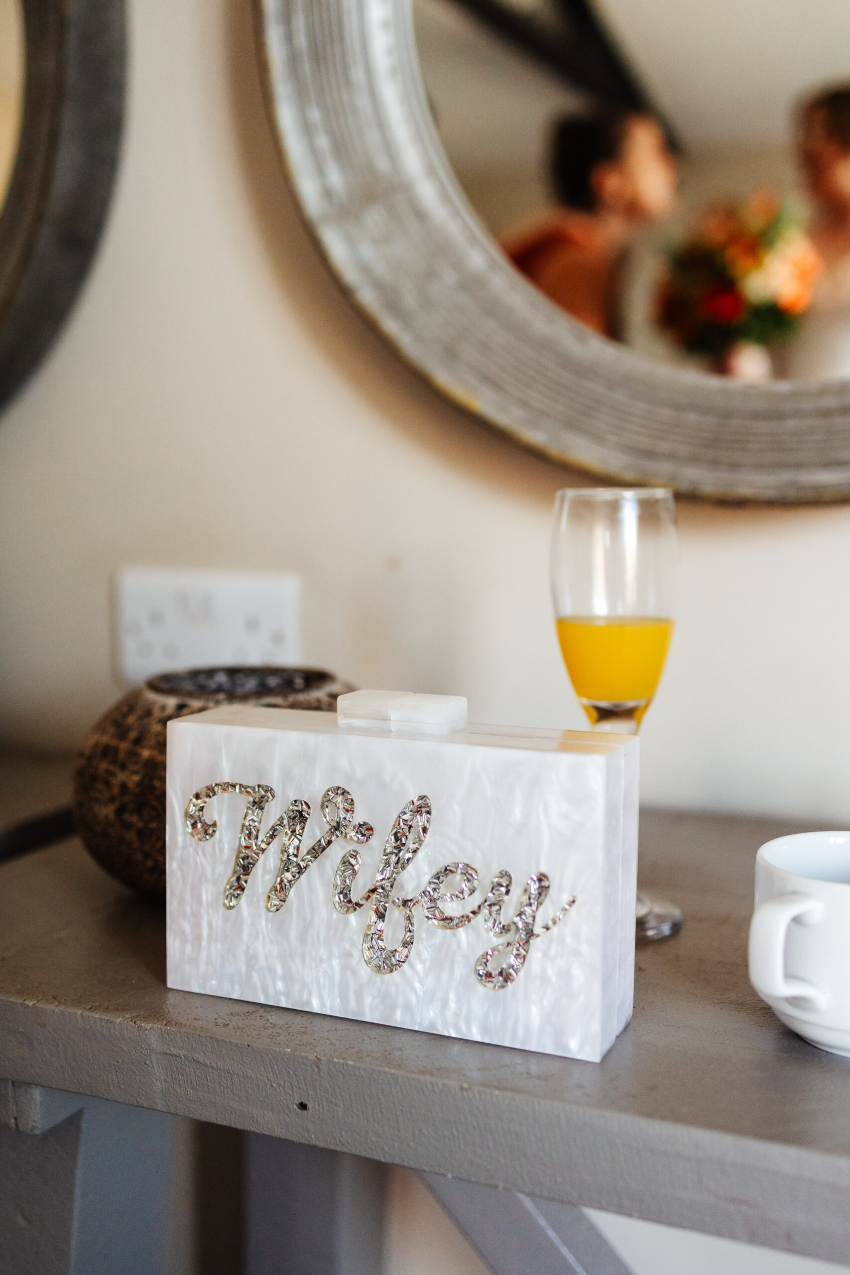 A photo of a white marble effect bag. It has the word Wifey written on it in silver jewells.