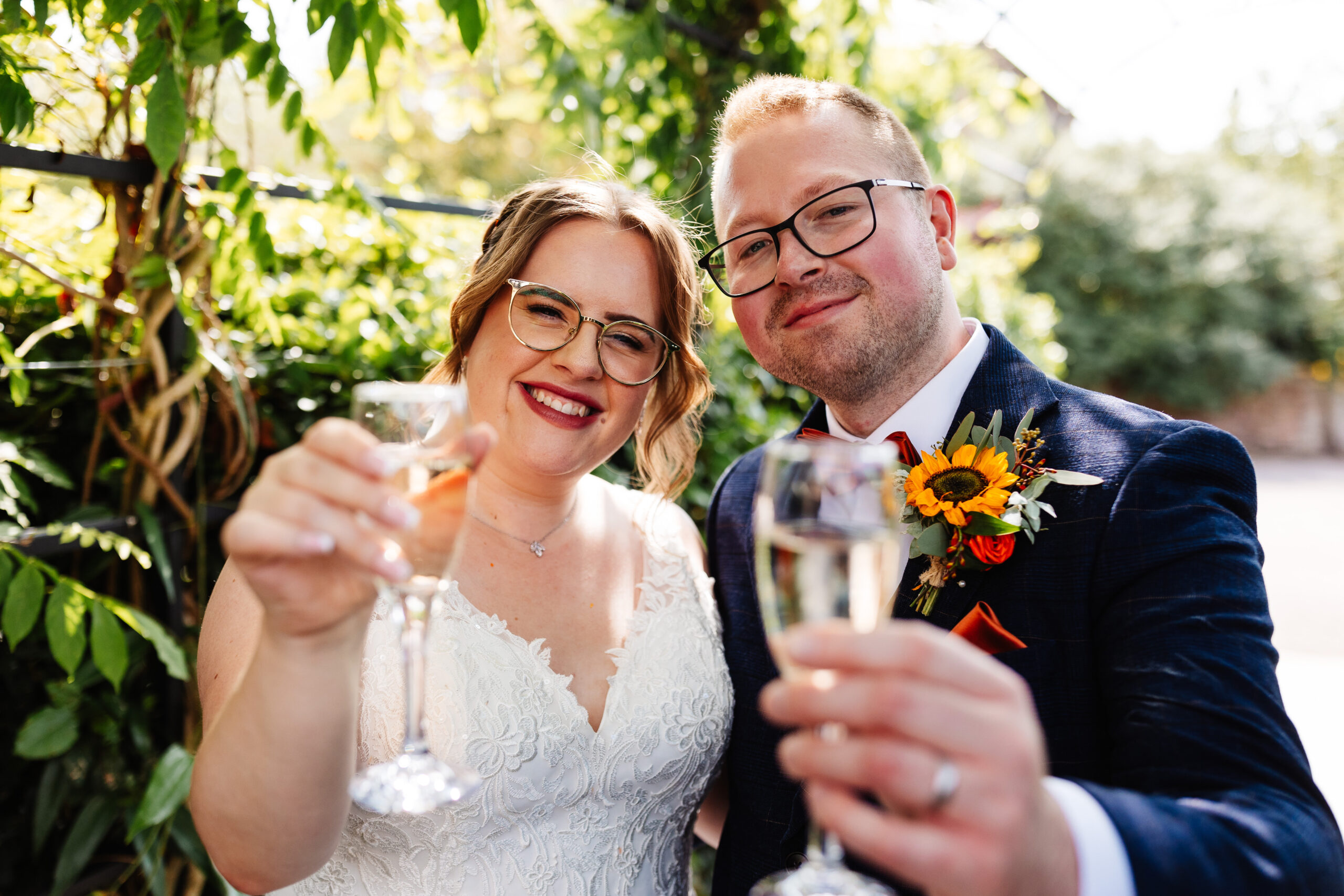 The newly married couple with a glass of champagne. They are looking at the camera and smiling.