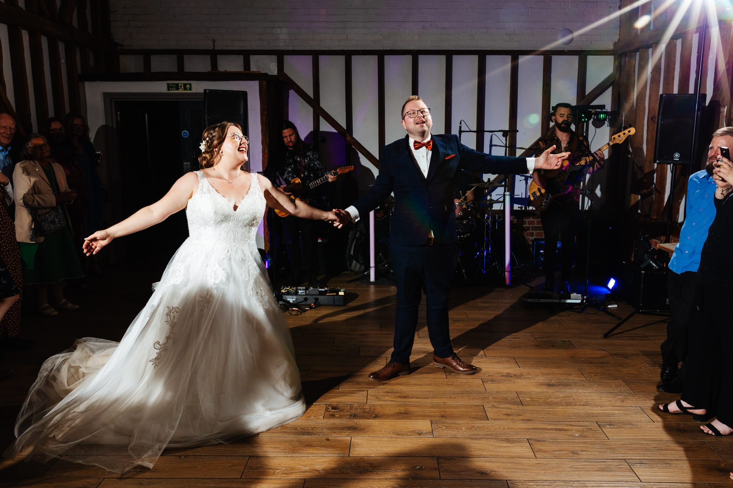 The bride and groom on the dancefloor. They are dancing and there is a band in the background.