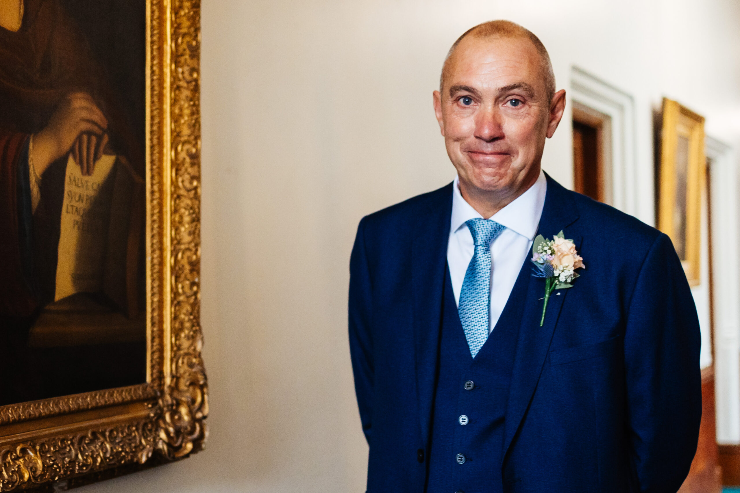 The bride's father. He is in a blue suit. He is about to go and see his daughter in her dress for the first time. He is already tearful.