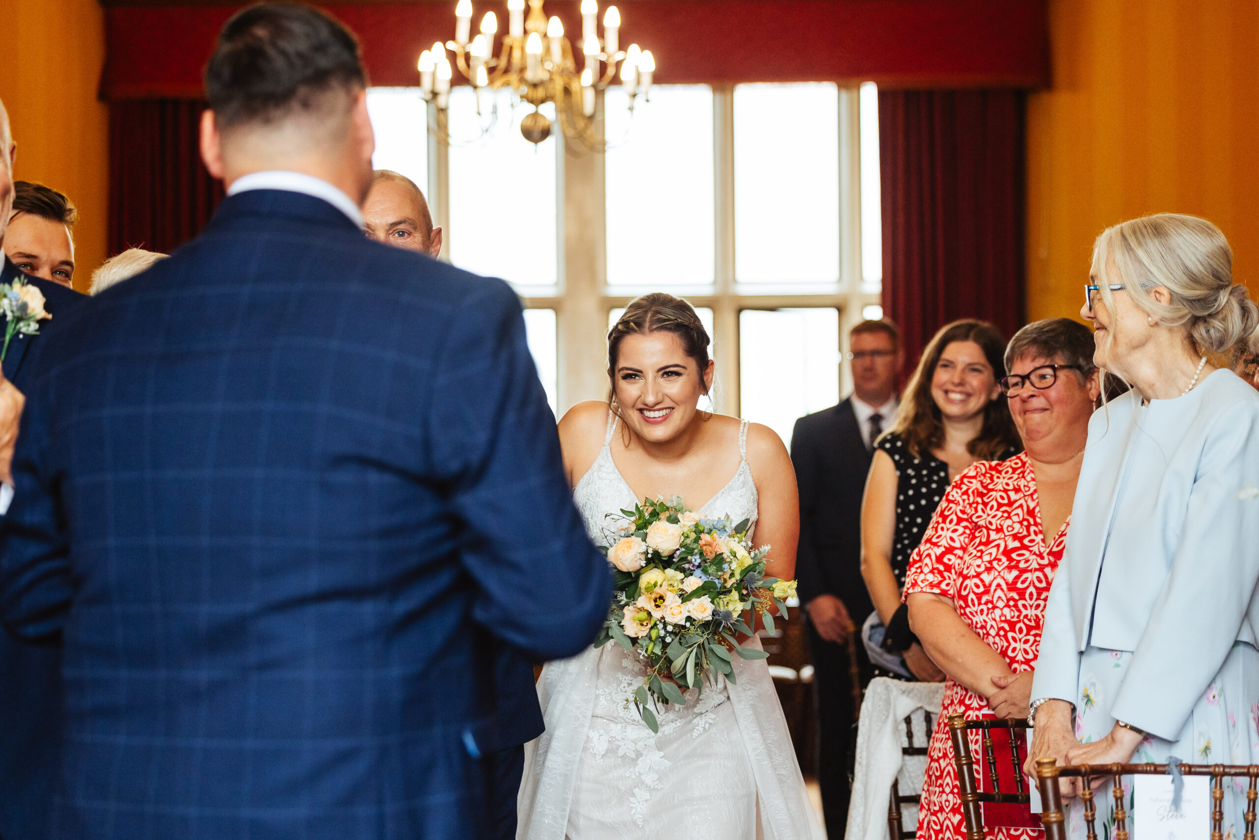 The back of the groom and the bride looking at him. She looks happy and is smiling looking directly in to his eyes. She is very happy.