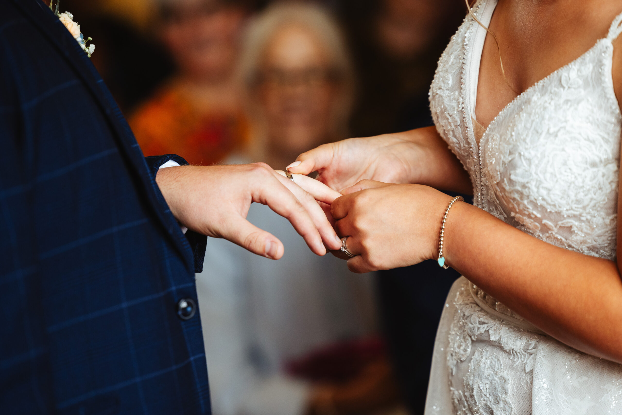 The bride and groom's hands. They are exchanging rings.