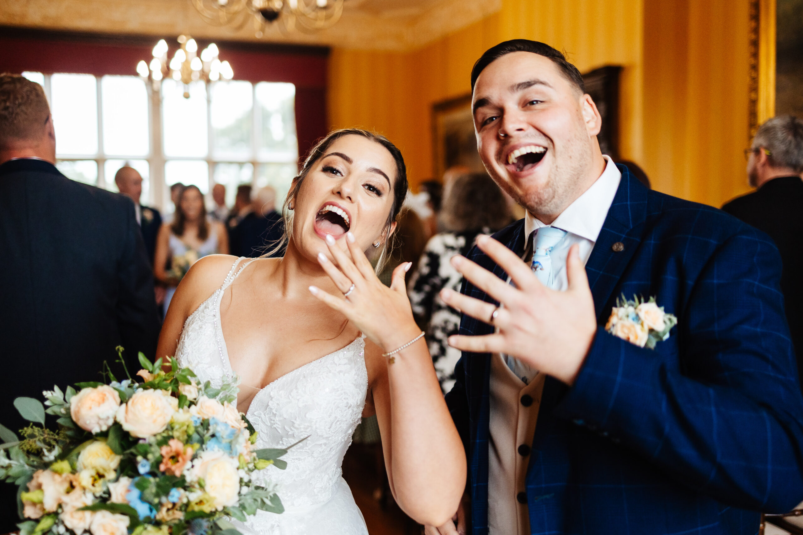 The bride and groom after their marriage. They are showing off their wedding rings, they are smiling and looking at the camera with excited faces.