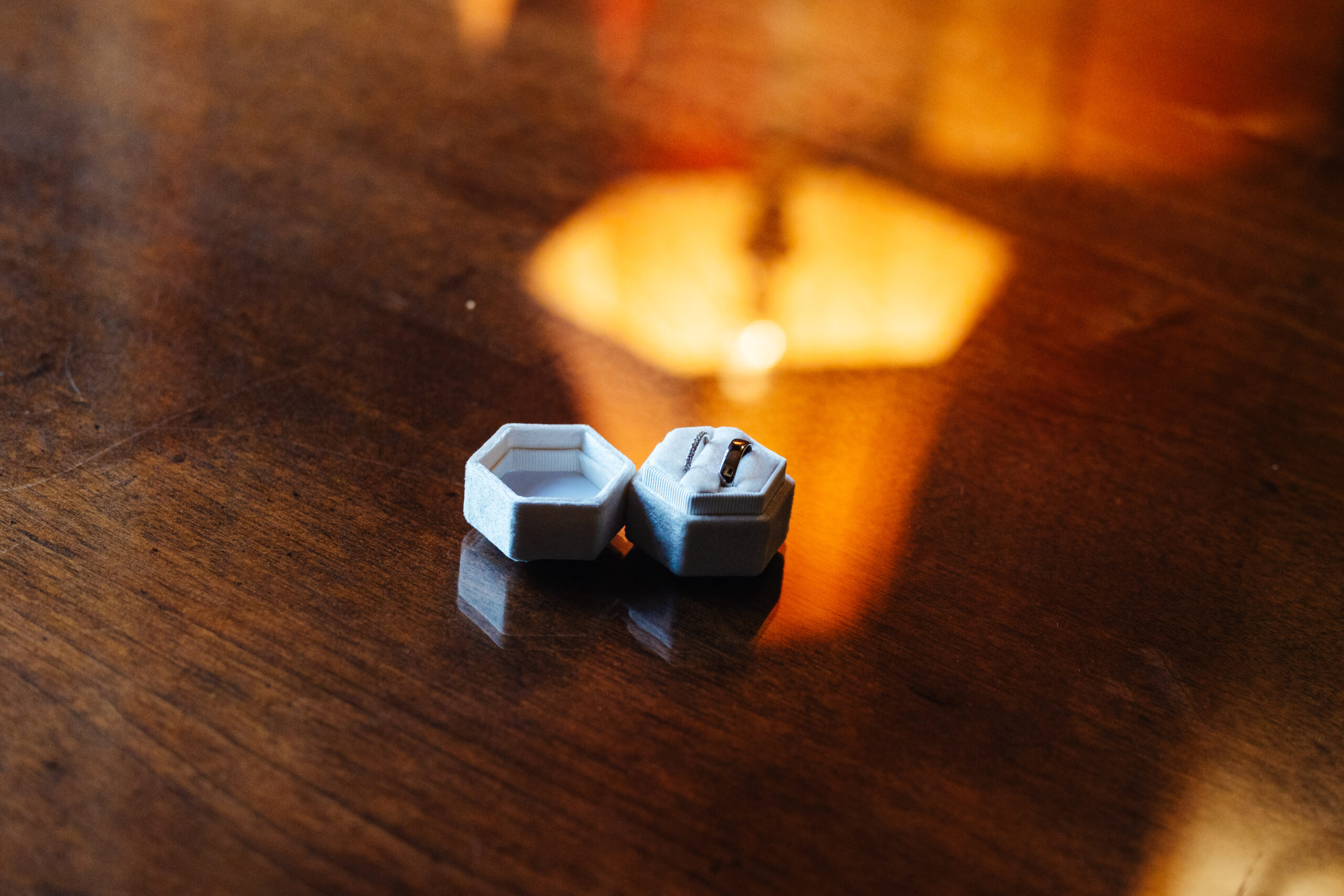 A photo of a pale blue ring box with two rings in side it. It is on a wooden table.