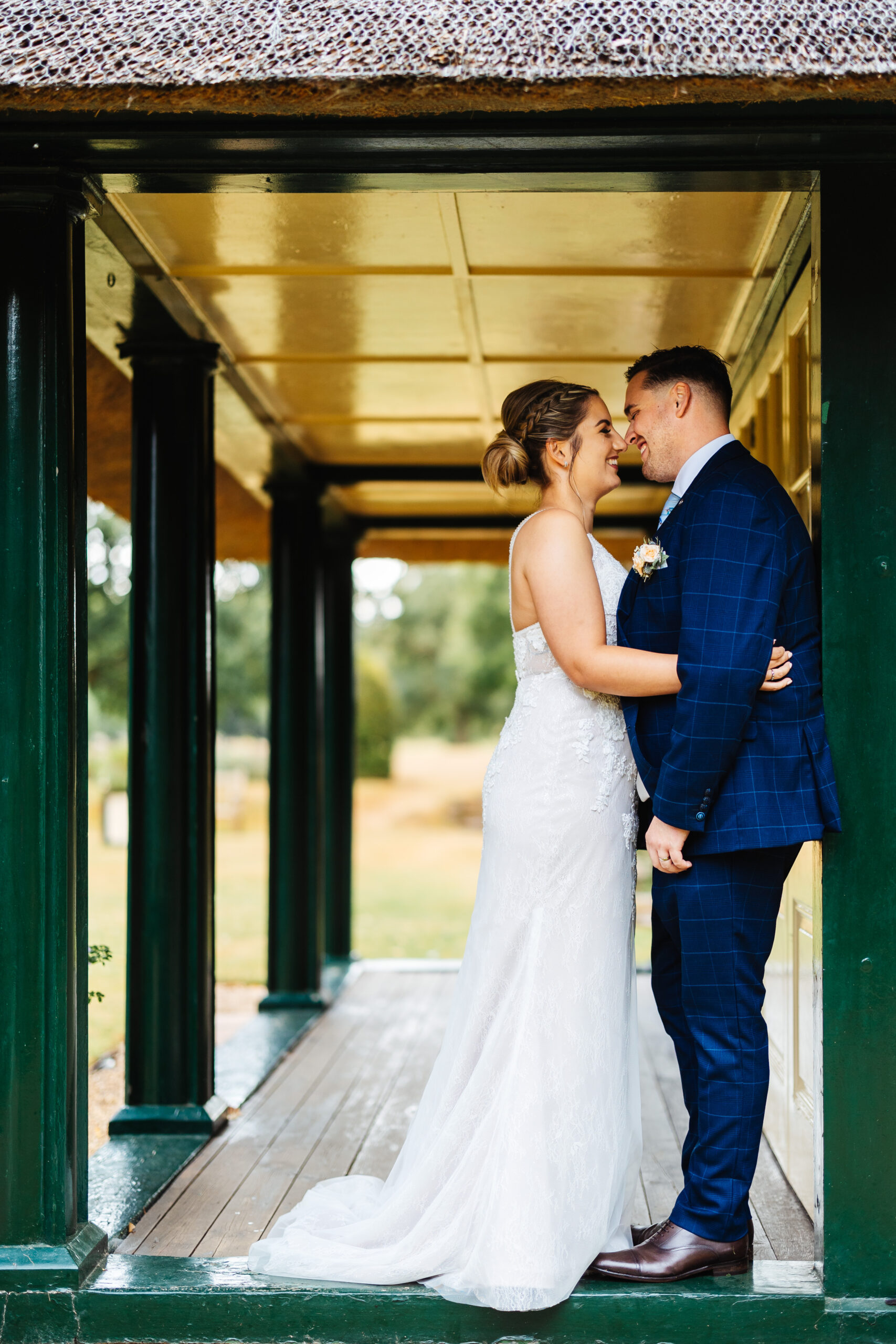 The bride and groom embracing one another. They are in a doorway which is painted dark green.