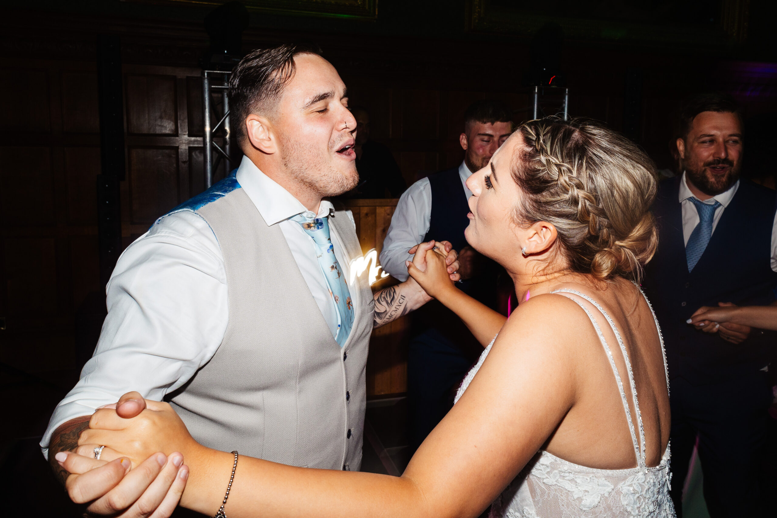 The bride and groom holding hands, facing one another with their eyes shut and they are singing.