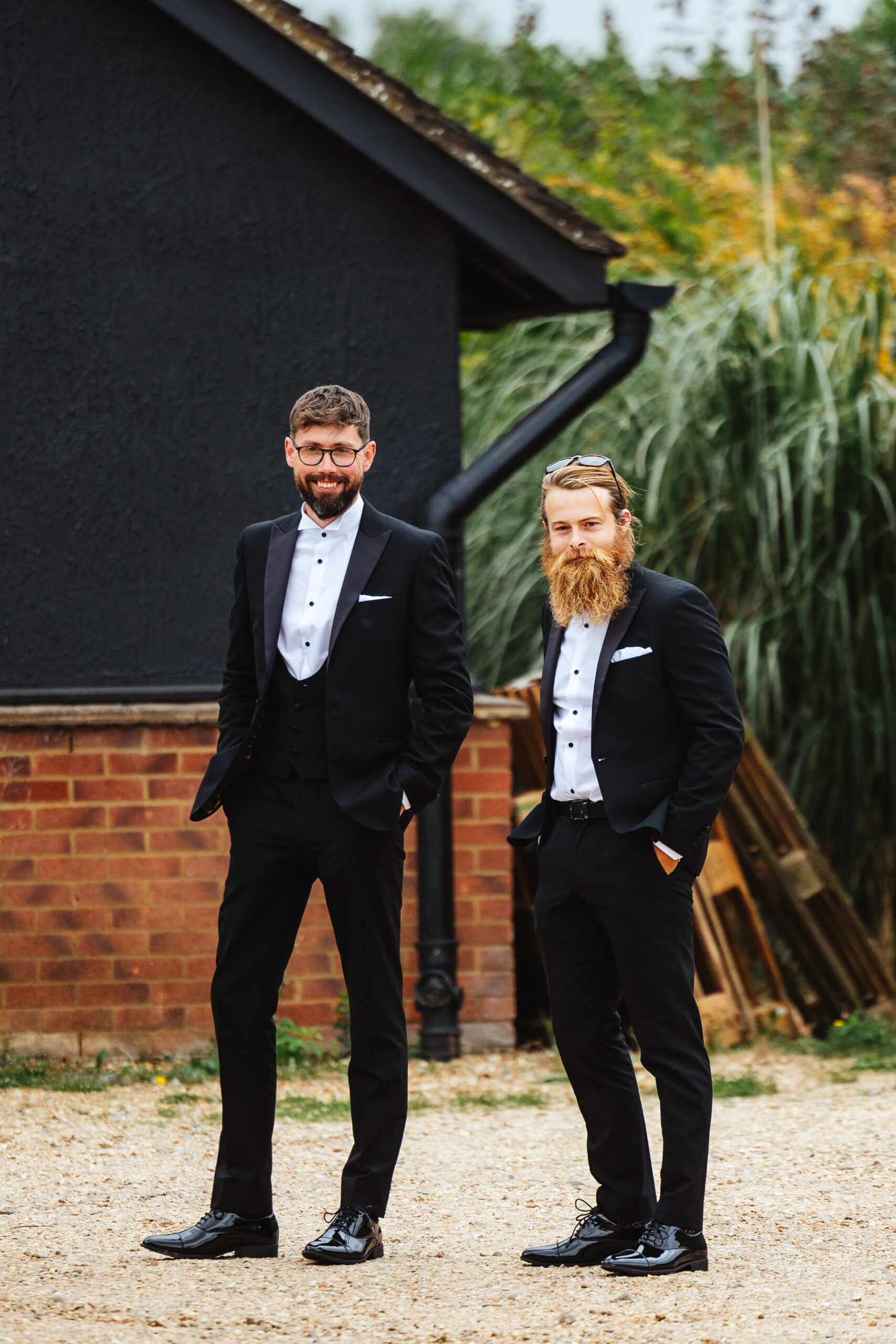 The bride and a groomsman. They are both wearing black tux and are smiling at the camera. They look relaxed.