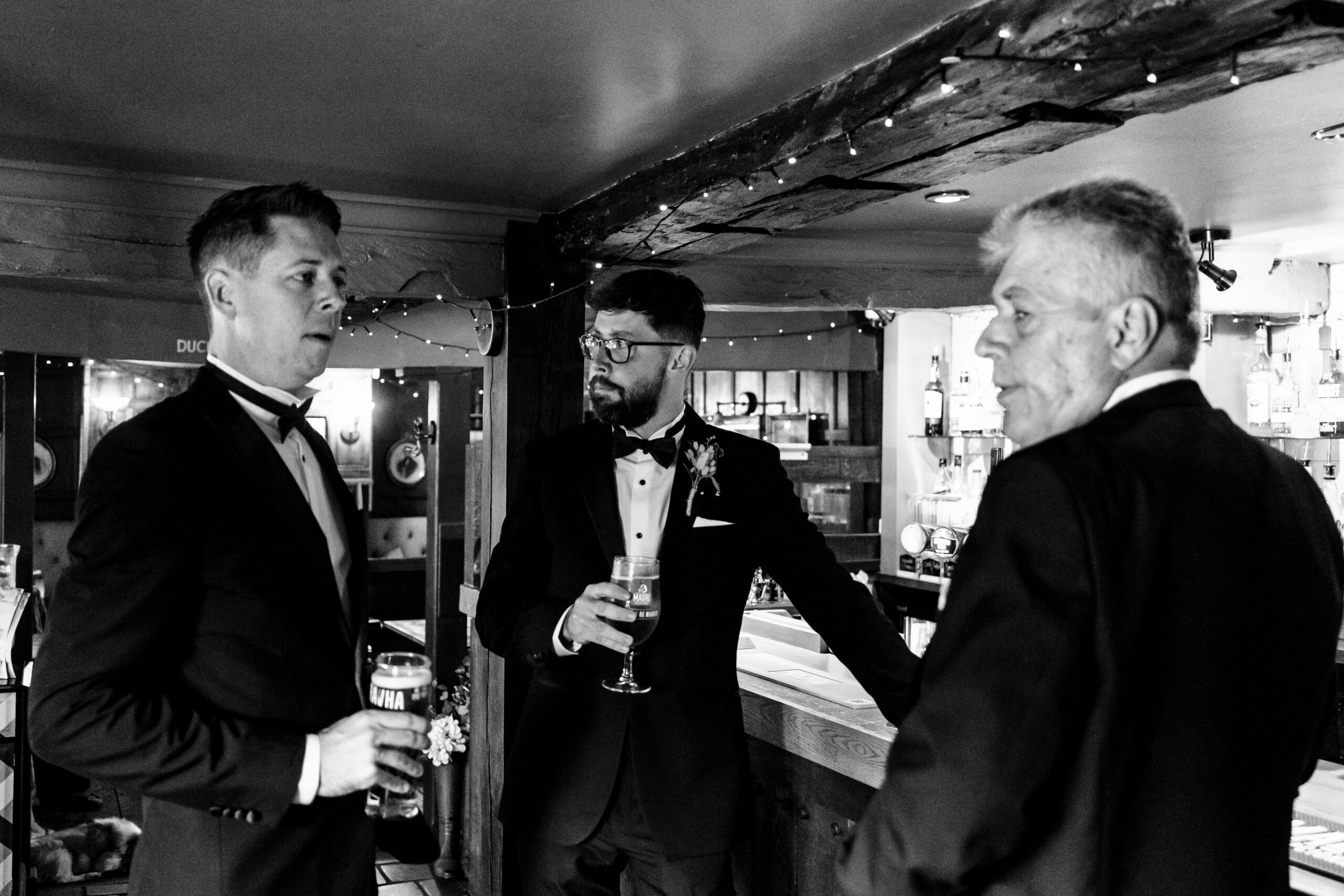 The groom, his father and a groomsman. They are wearing black tux and are enjoying a beer.