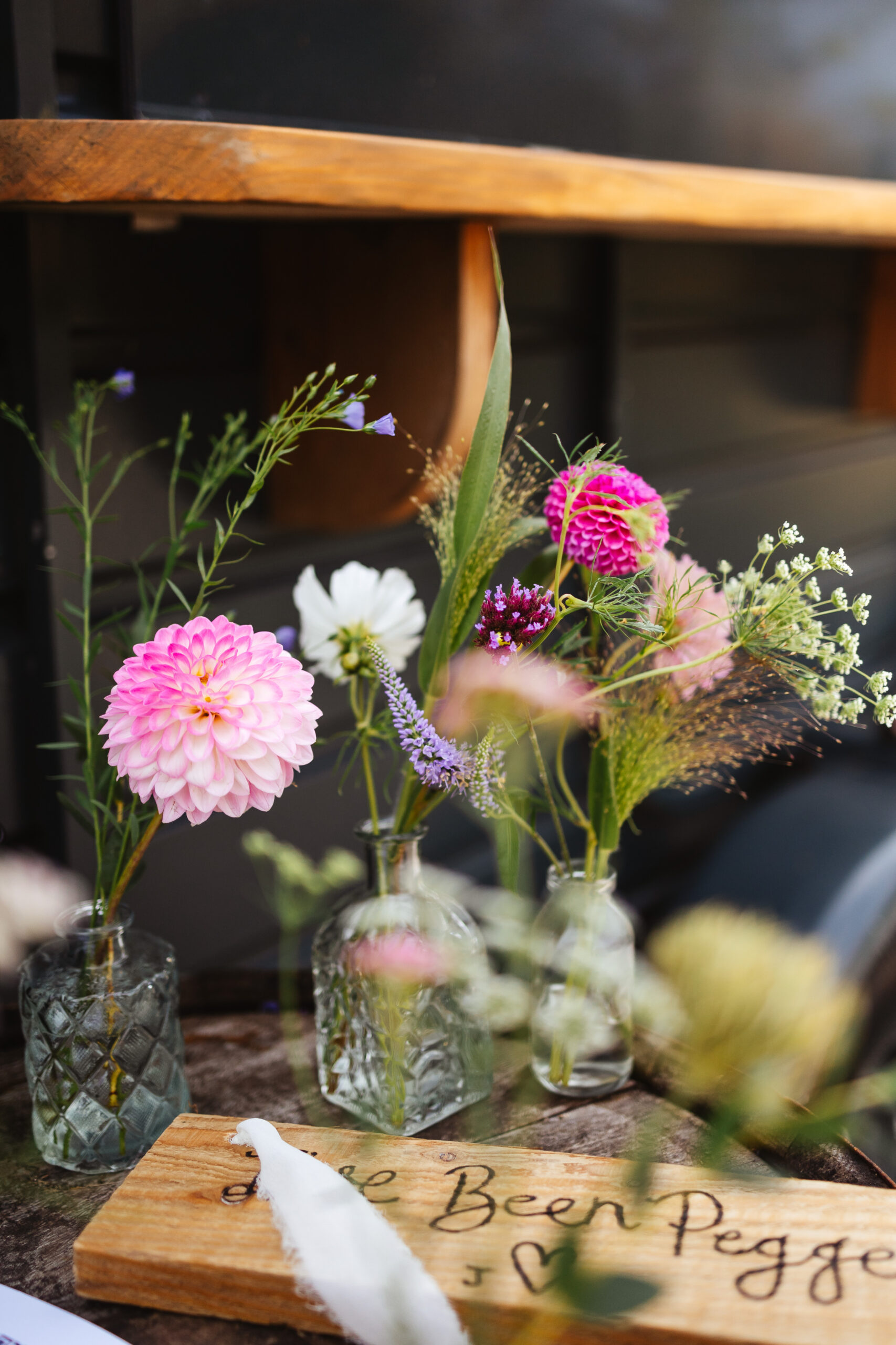 Little jars of single flowers. The flowers are pink, dark pink and purple.