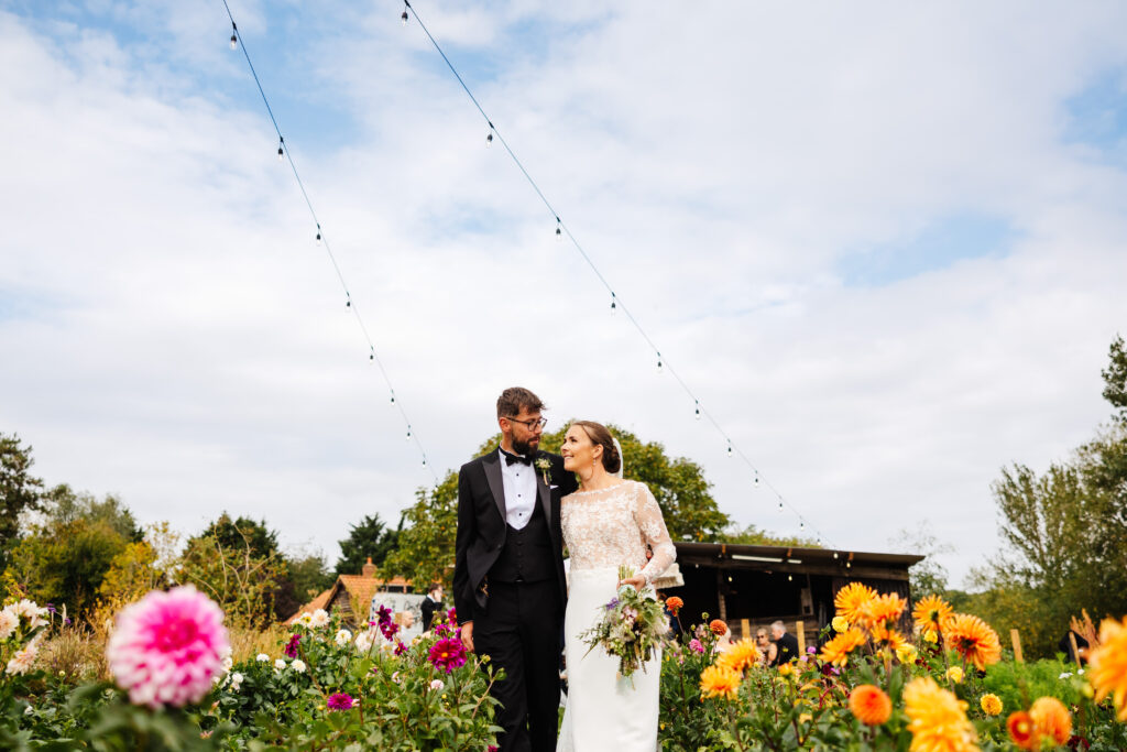 bride and groom stood close together in a field of dahlias on a flower farm