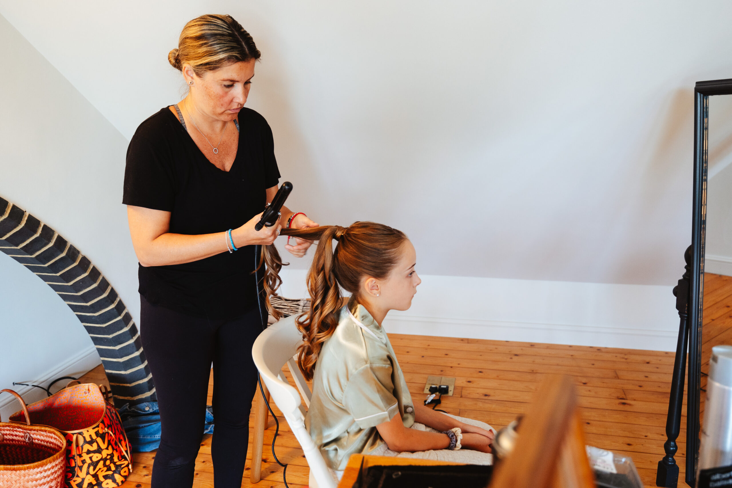 A hairdresser doing the hair of a little girl. She is having her hair curled.