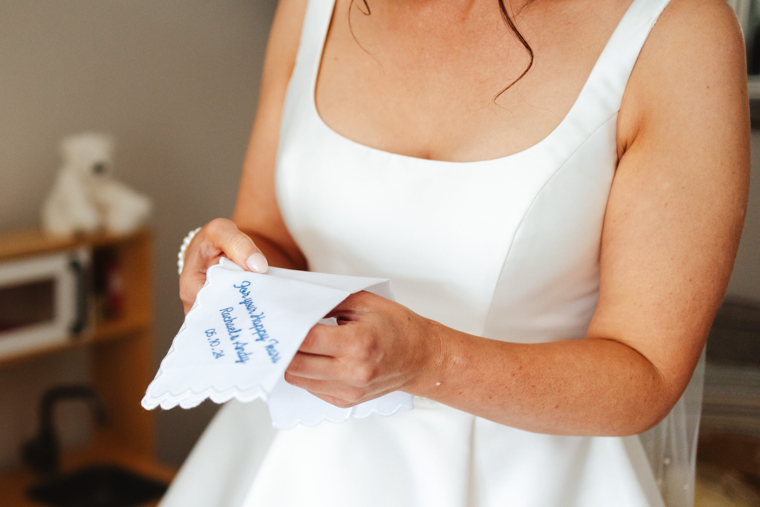 The bride holding a napkin. It has the words 

For your happy tears, Rachael and Andy and the date of the wedding embroidered on to the napkin.