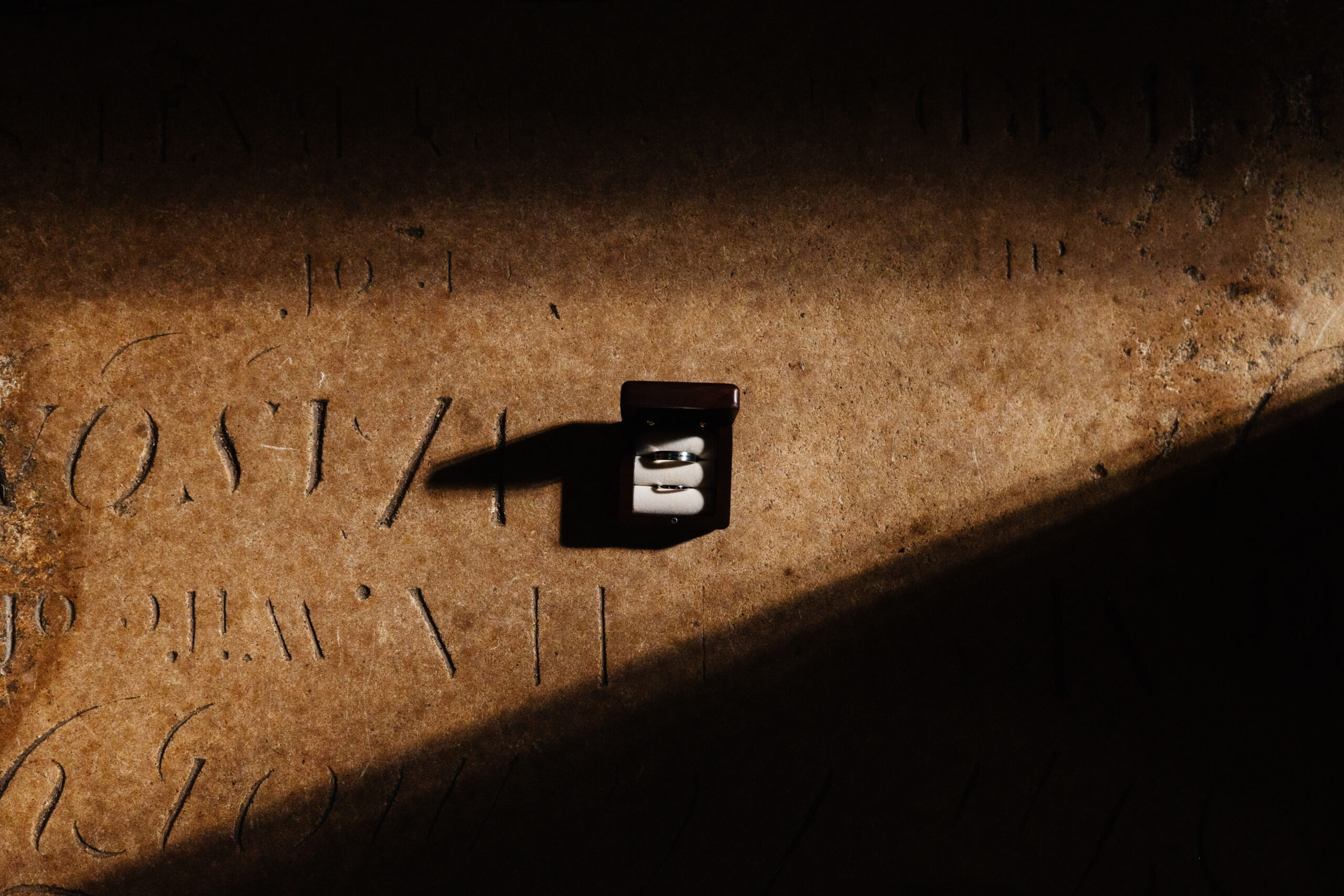 An image of two rings in the ring box on a concerete floor of the church where the couple will be getting married.