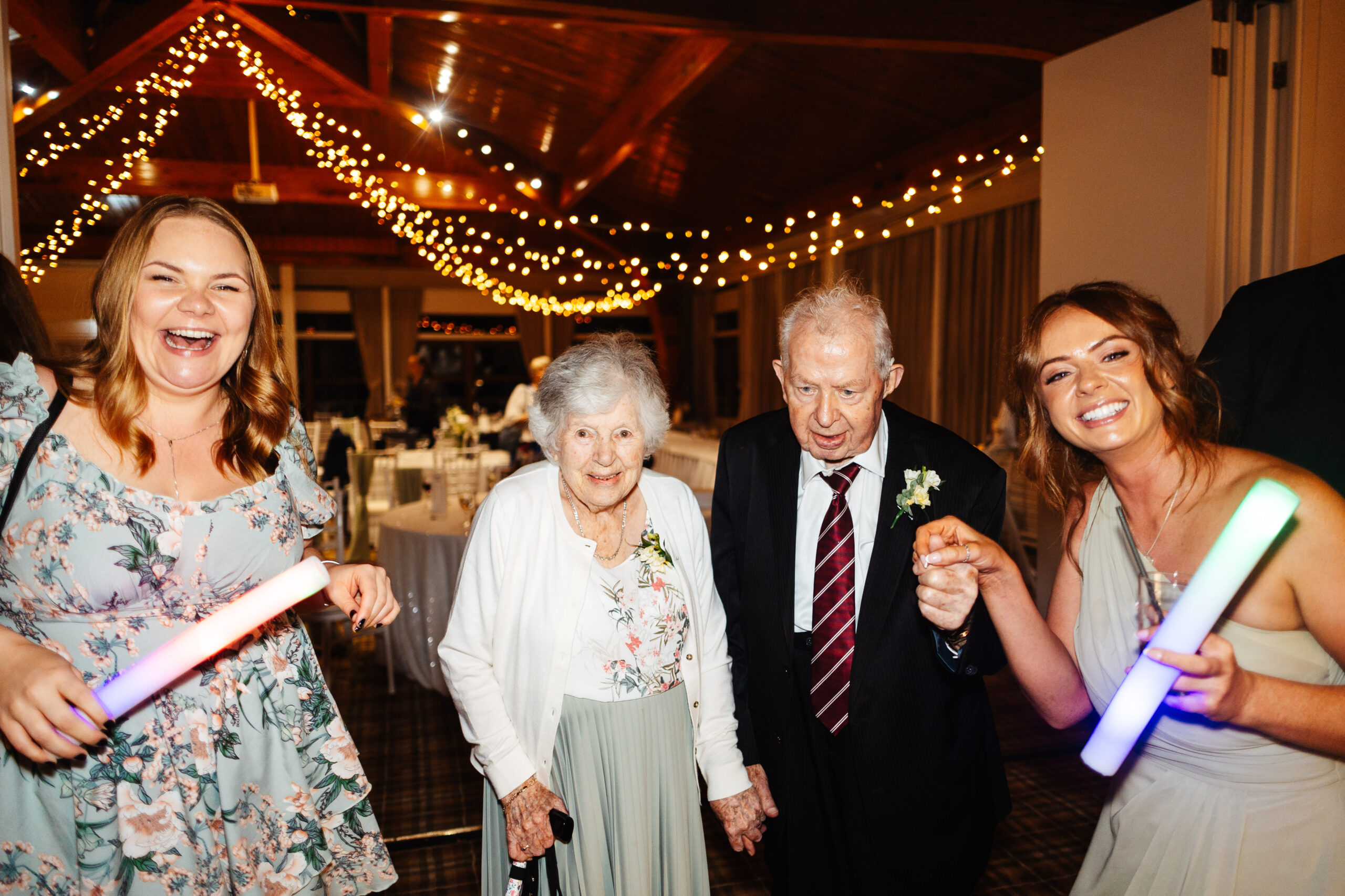 Four guests at the wedding on the dance floor. There is an elderly couple who are holding hands and look like they are about to dance.