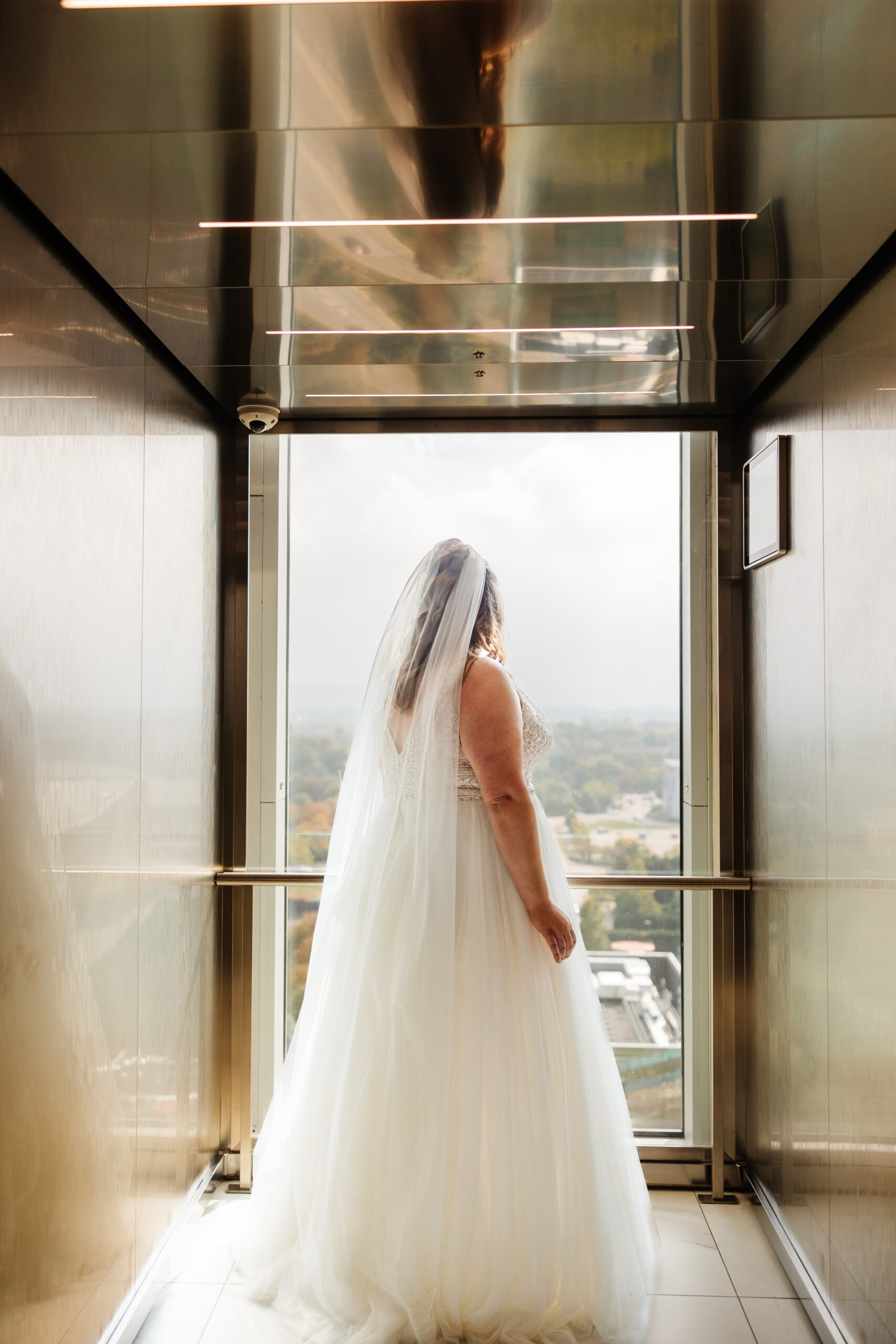 The bride in the lift about to go downstairs to get married. You can see her looking out of the clear side of the lift which is over Milton Keynes. 