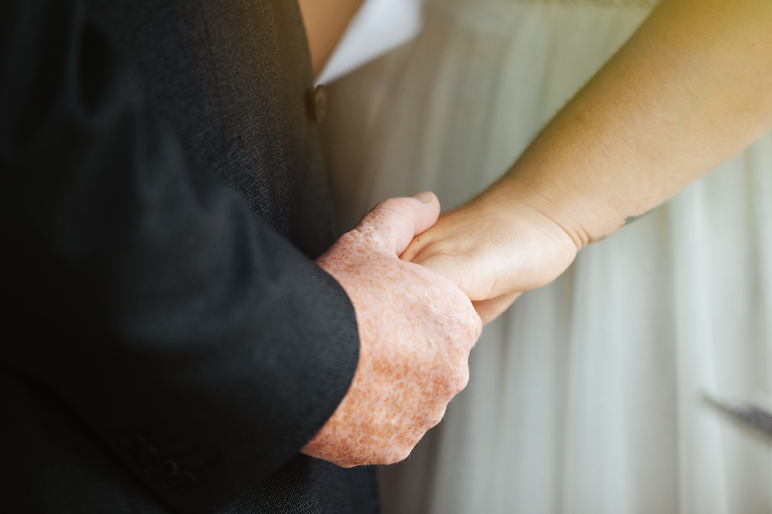 The bride and groom's hands. They are holding hands.