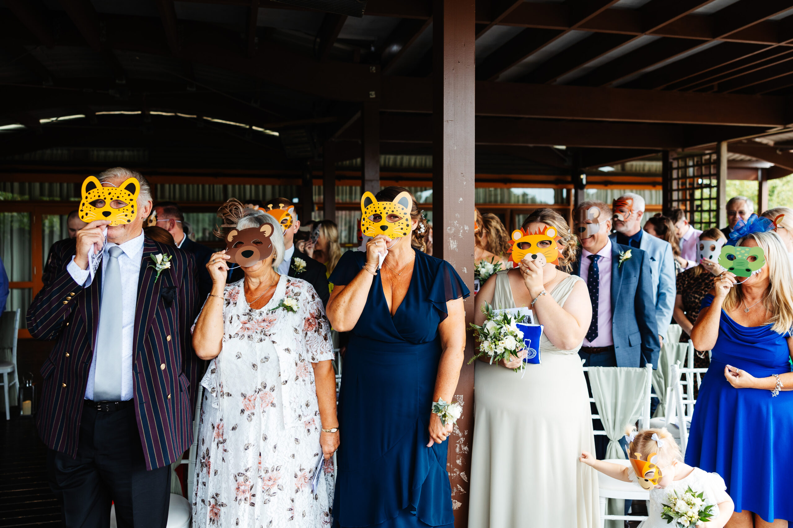 Guests holding up animal masks to their faces. There is an array of animals including a leopard, crocodile, lion and cheetah.